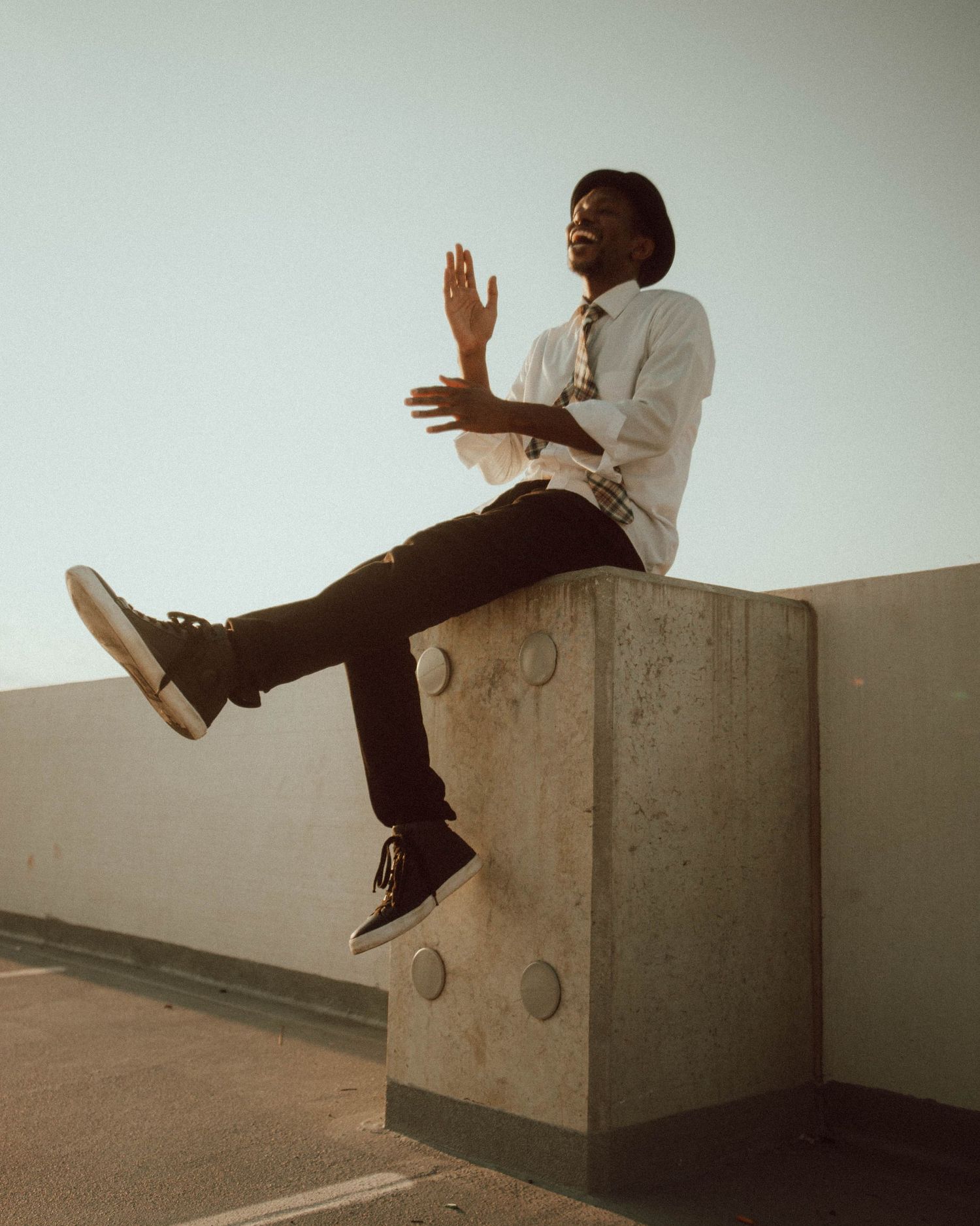 A sequence of photos showing someone in business attire sitting and jumping on a concrete ledge in an artistic pose.