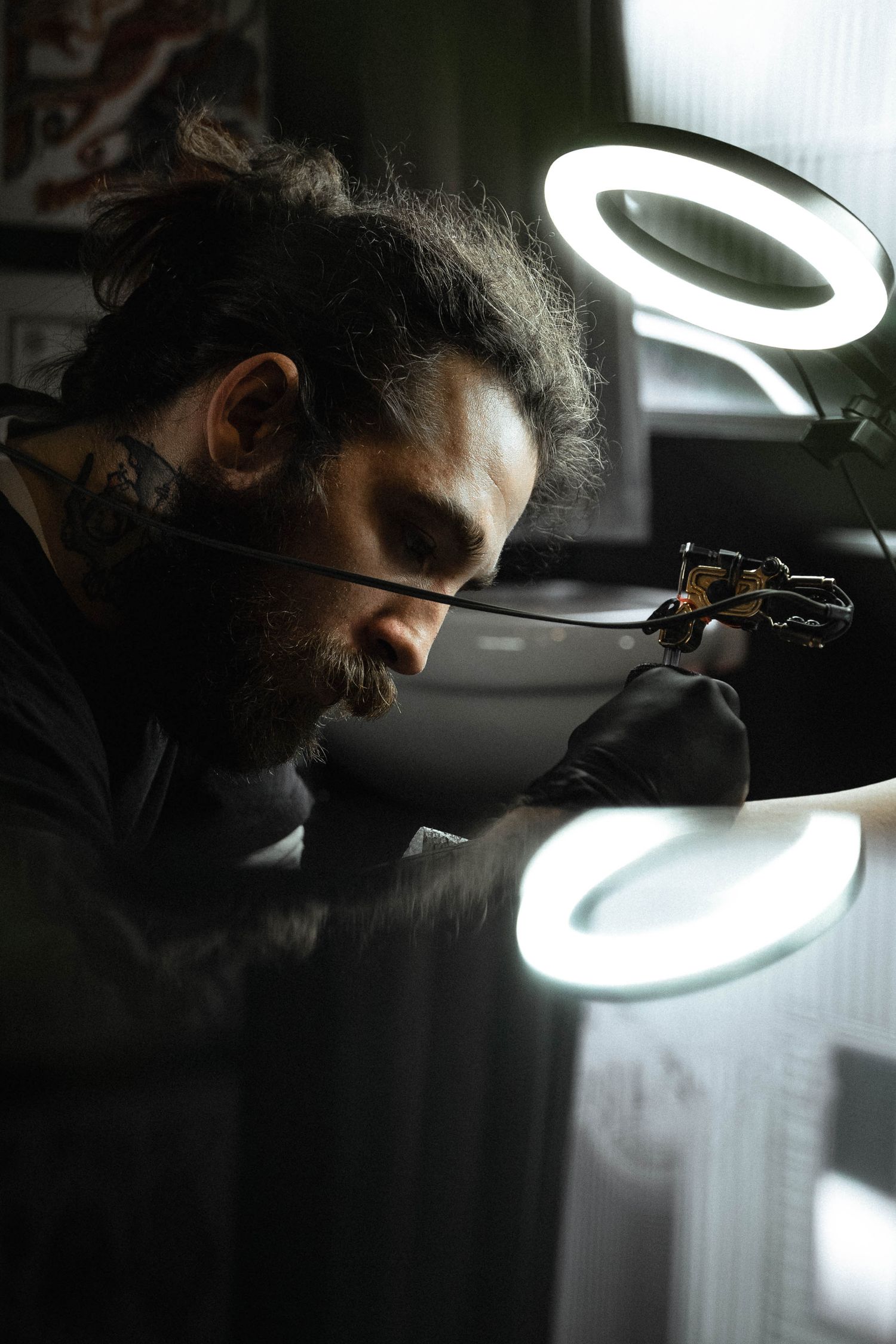A person works in low light conditions under circular LED lamps casting dramatic shadows and illumination.