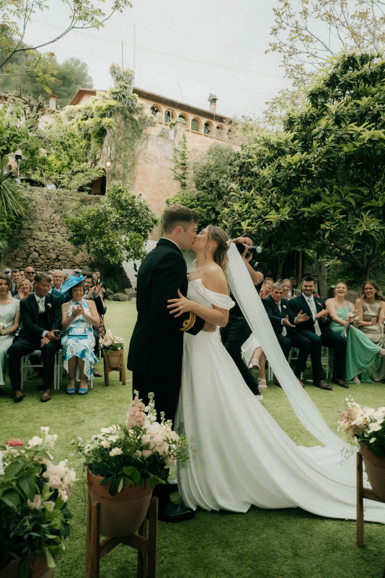 First kiss at outdoor wedding ceremony in Barcelona with flowing veil and garden venue