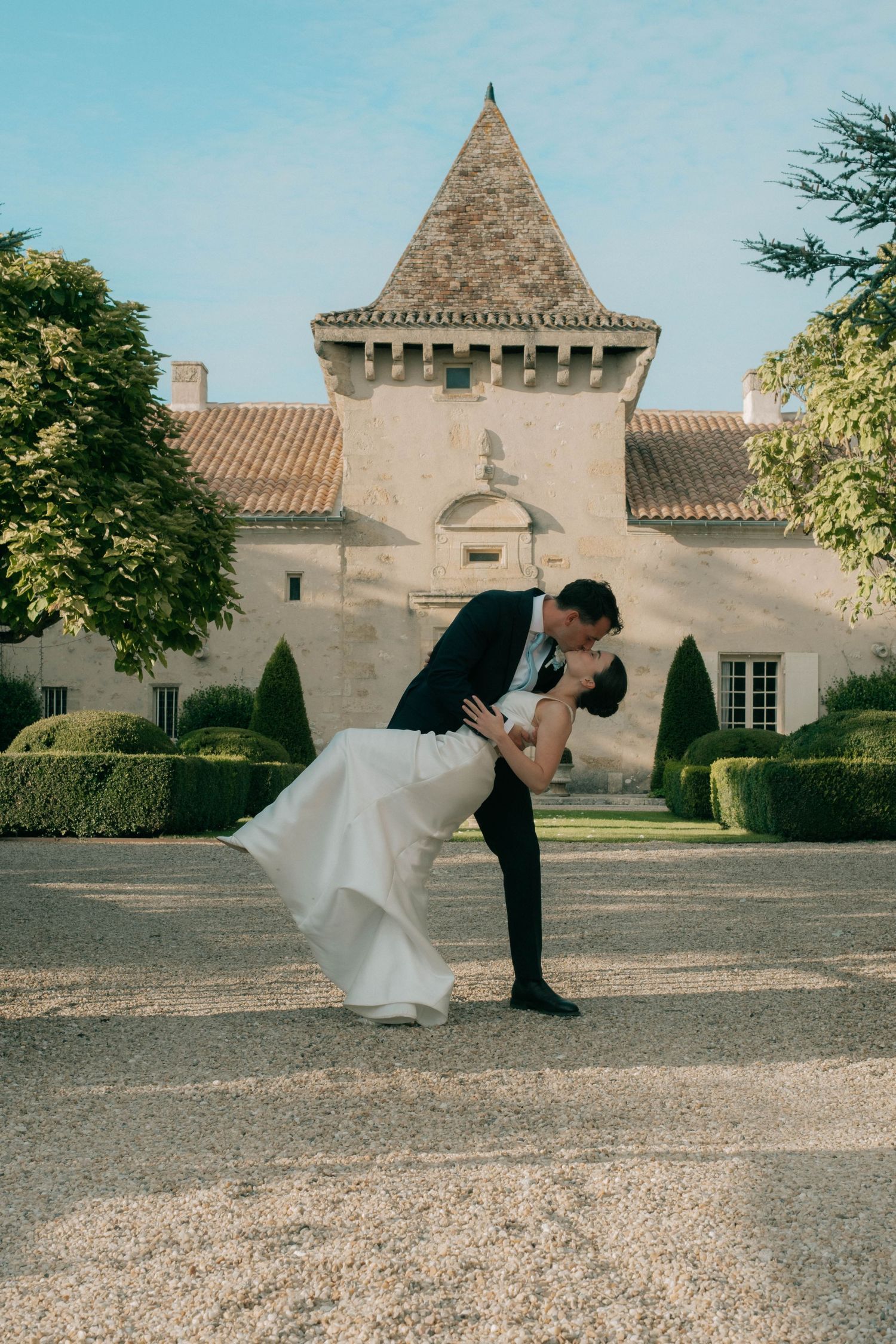 Bride and groom kissing in front of French château during destination wedding in Europe.