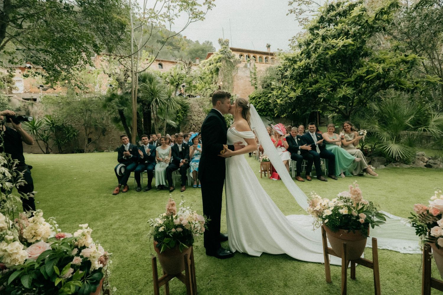 First kiss at outdoor wedding ceremony in Barcelona with flowing veil and garden venue