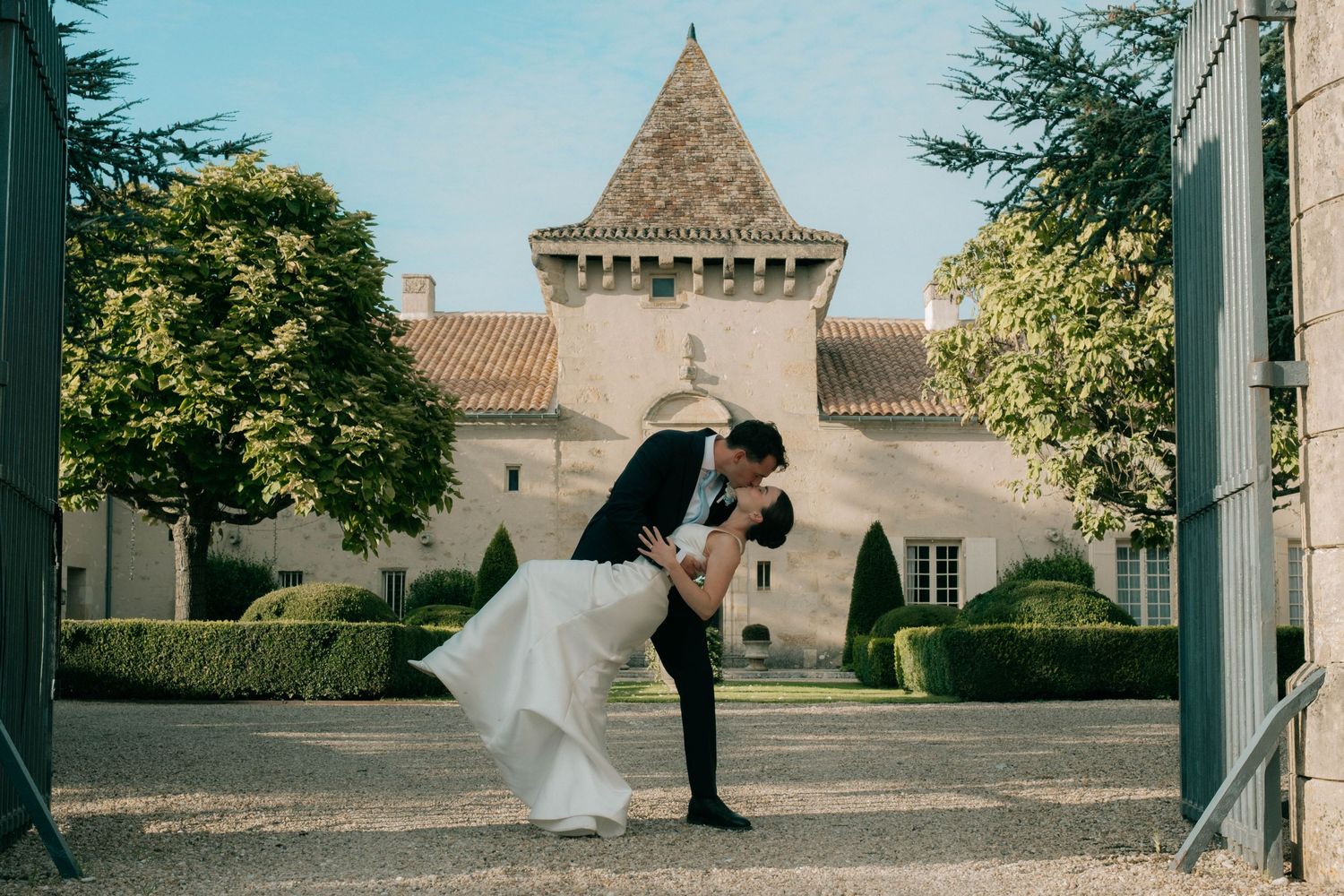 Bride and groom kissing in front of French château during destination wedding in Europe.
