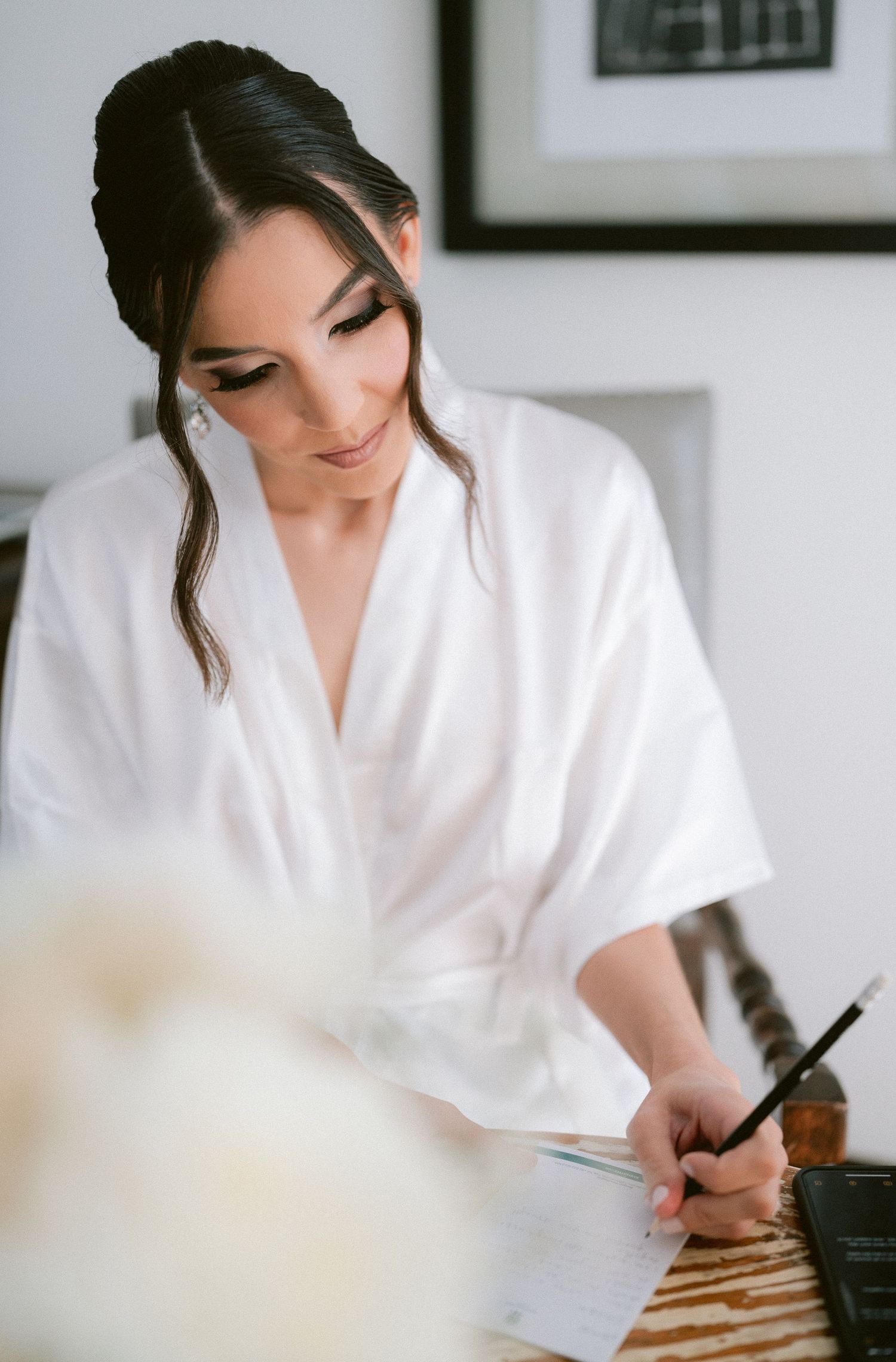 Beautiful bride in white robe writing vows with calligraphy pen on her wedding morning.