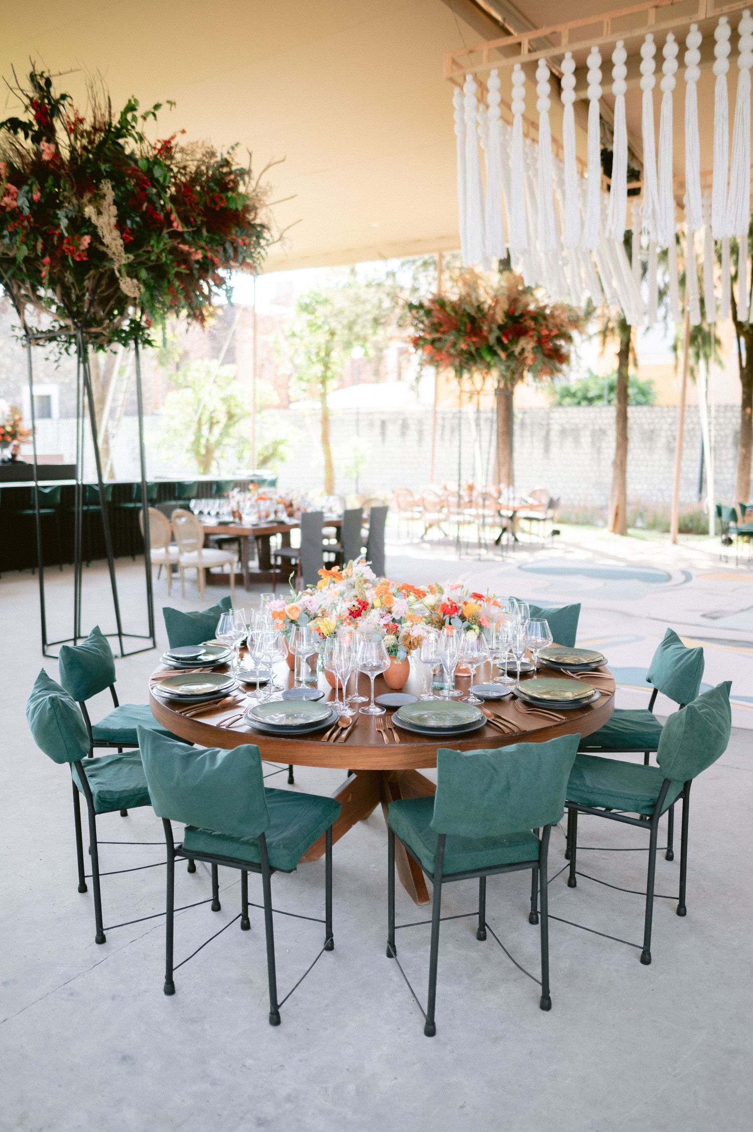 Elegant round wedding reception table with teal chairs and colorful floral centerpieces.