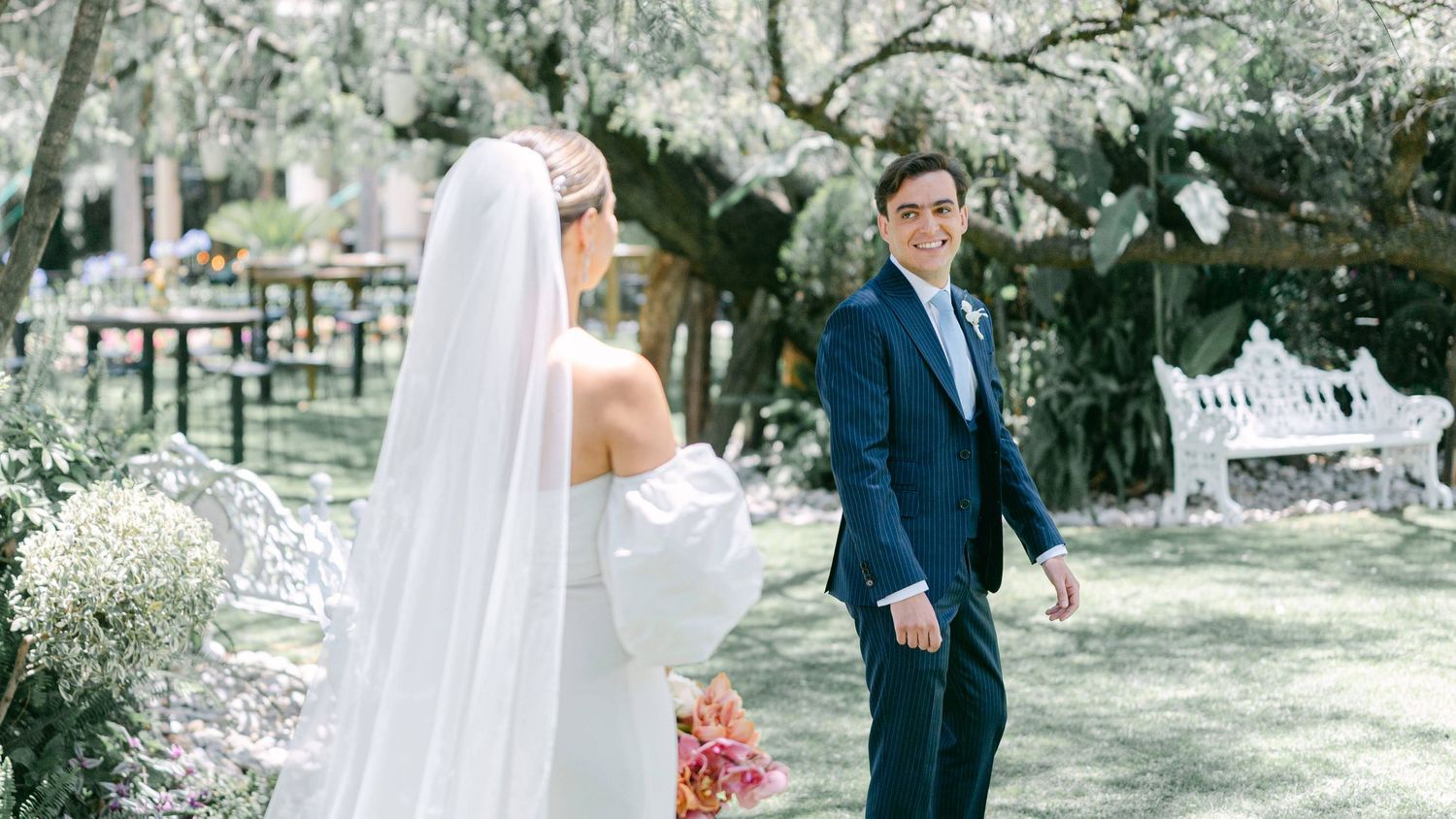 Groom in navy suit turning to see bride during outdoor first look wedding moment.