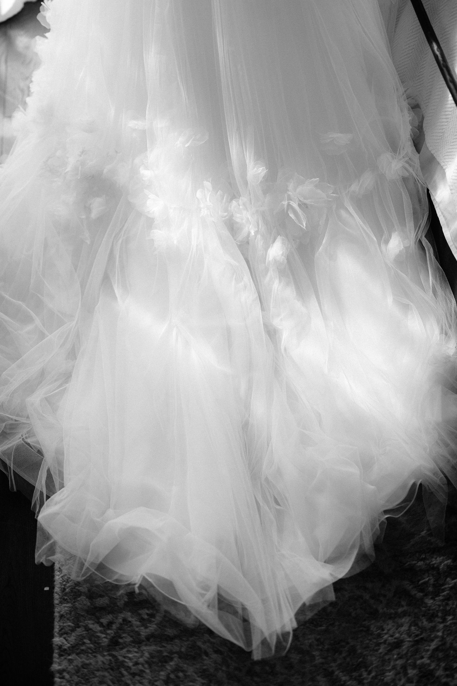 Black and white detail shot of voluminous tulle wedding gown skirt with feather embellishments.