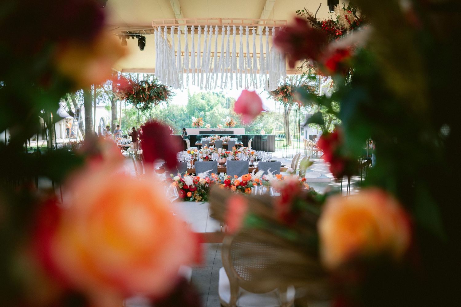 Romantic wedding reception venue viewed through vibrant pink and orange floral arrangements.