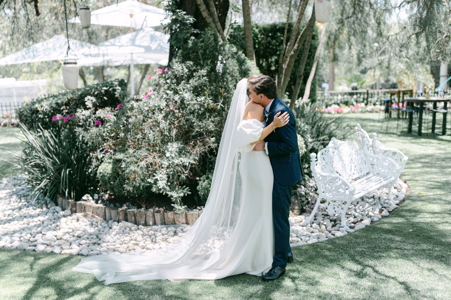 Bride and groom sharing romantic embrace kiss in beautiful garden wedding setting.