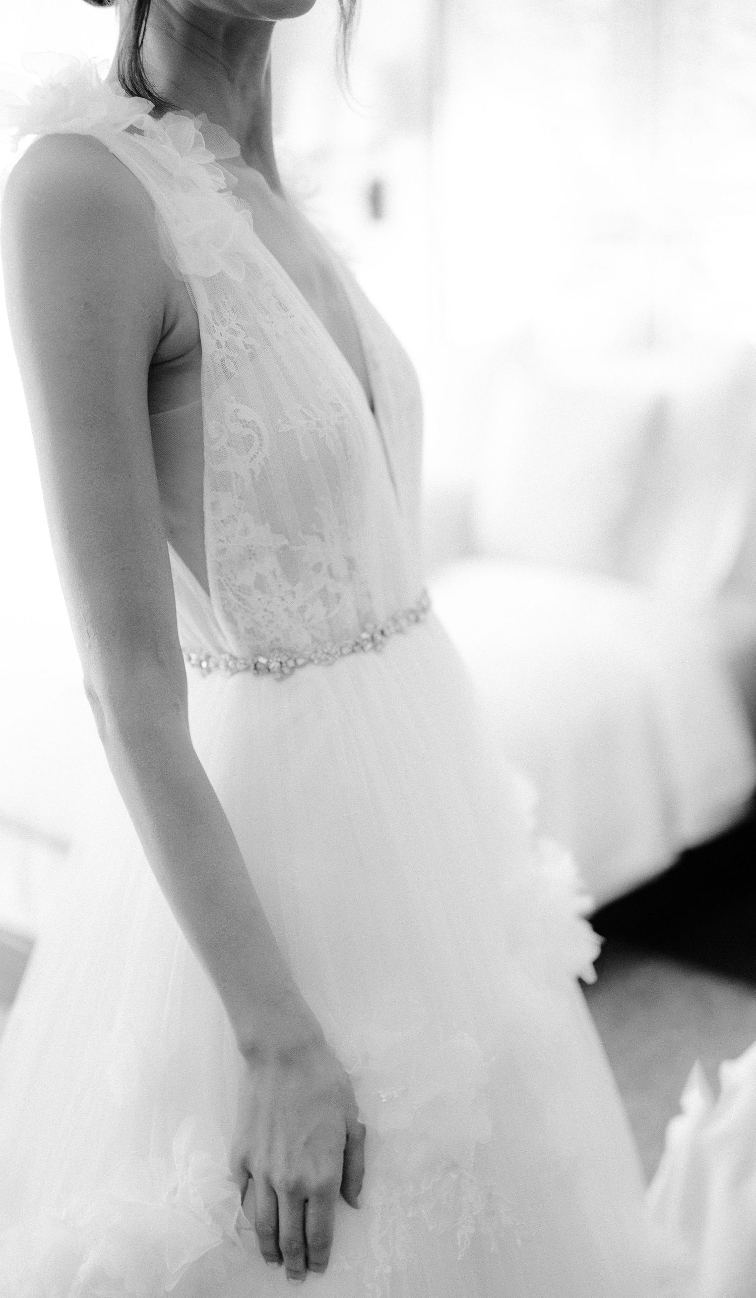 Black and white close-up of bride in stunning lace V-neck wedding gown with crystal belt.