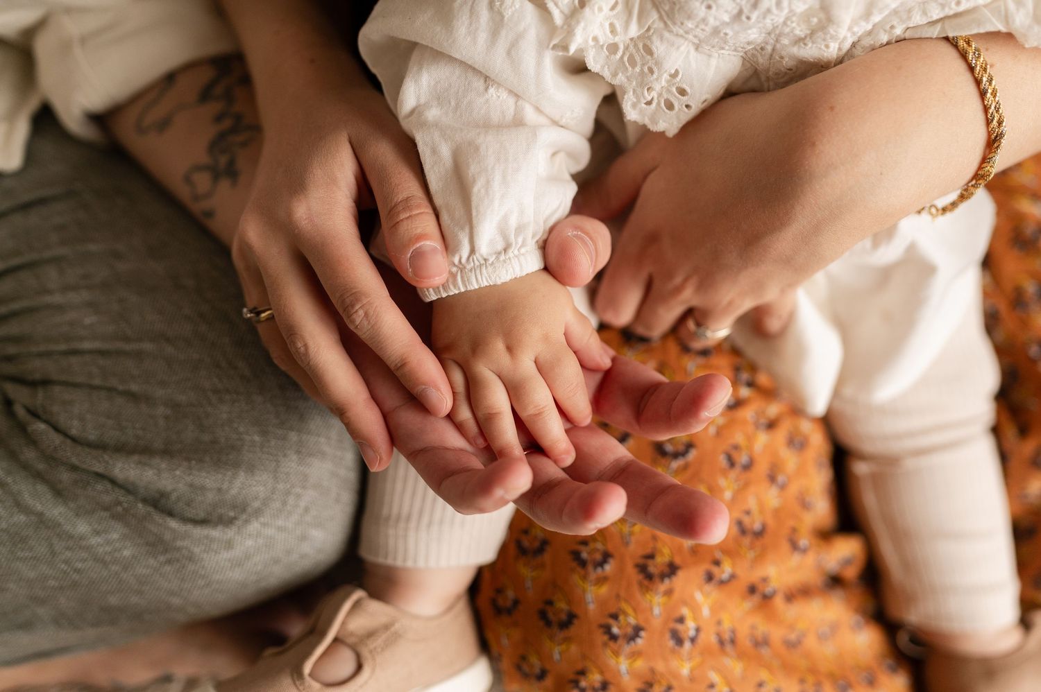Close-up of hands tenderly touching on a floral patterned fabric.