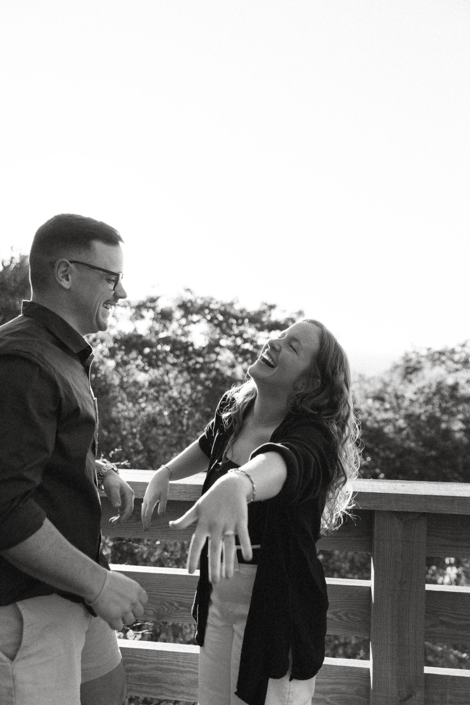 Candid black and white photo of a couple laughing together on a deck.