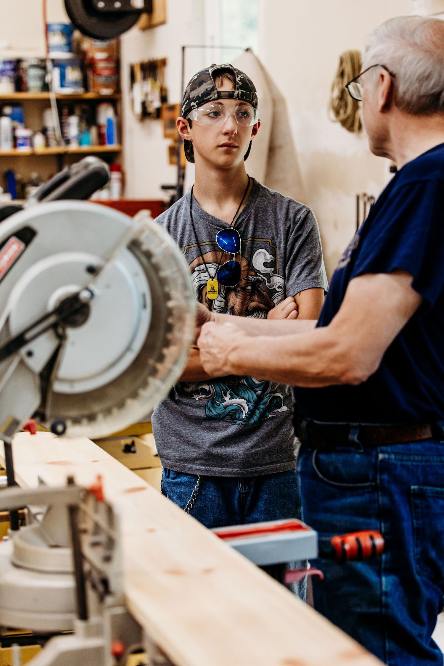 Teaching student how to safely operate a workshop miter saw through hands-on instruction and demonstration.