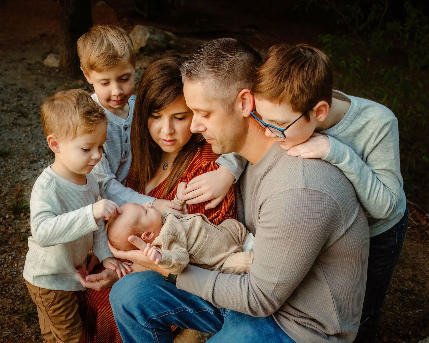 Family gathered closely together, lovingly gazing at newborn baby surrounded by three young children during family session in Keller, TX.