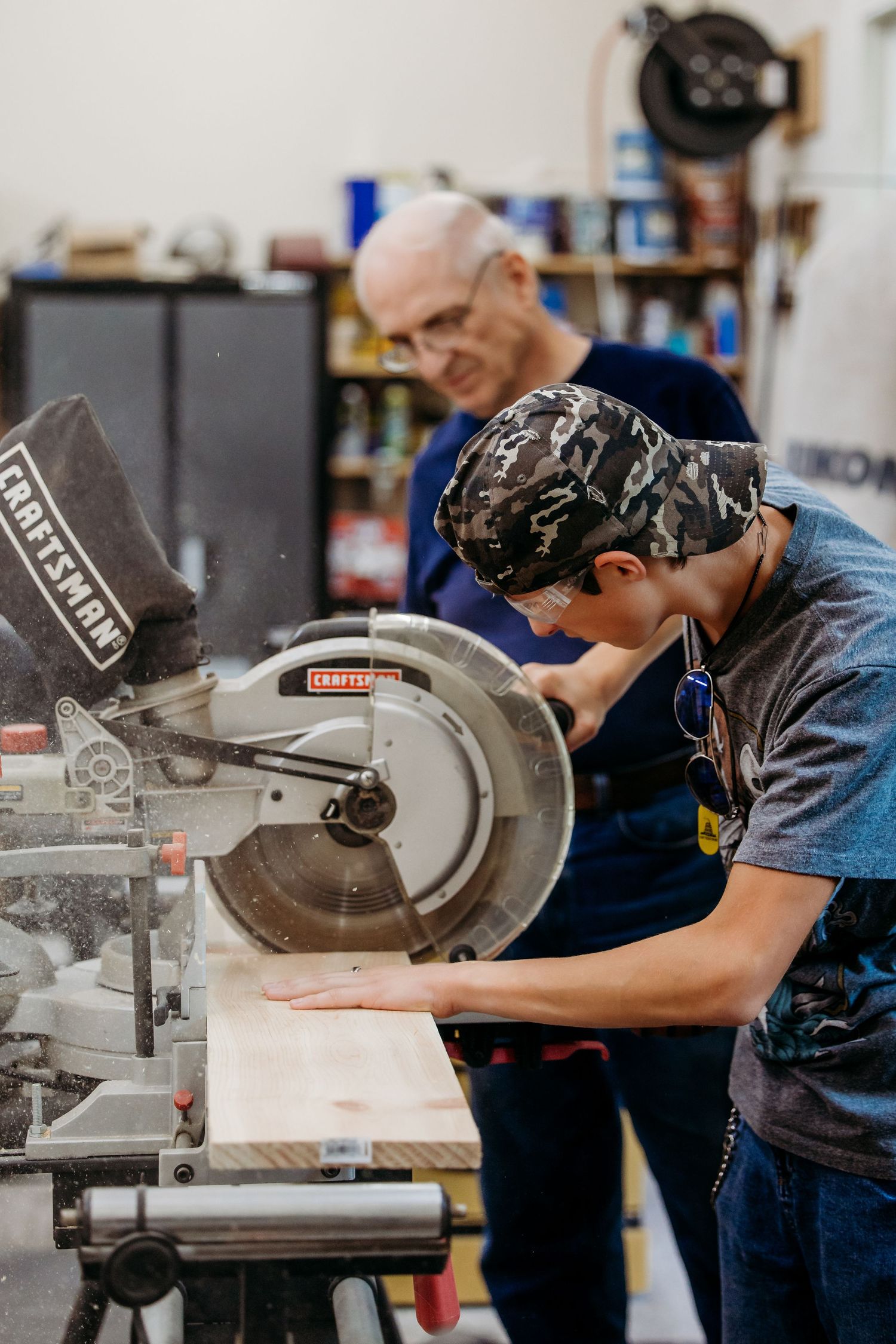 Workshop workers carefully operate table saws to cut wood pieces in a professional woodworking facility.