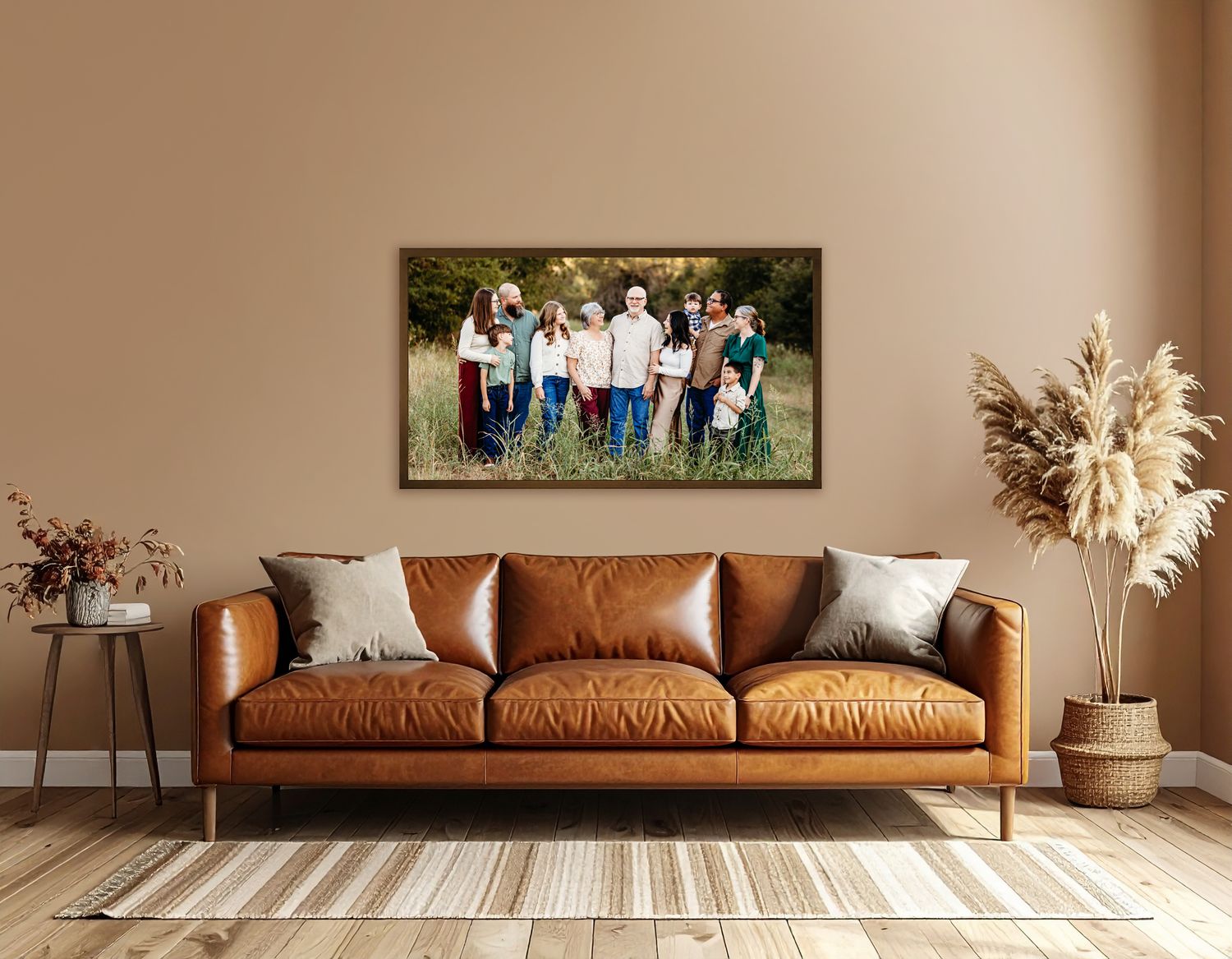 A brown leather couch sits against a wall in a minimalist living room with a large family portrait hanging above it in Keller, TX.
