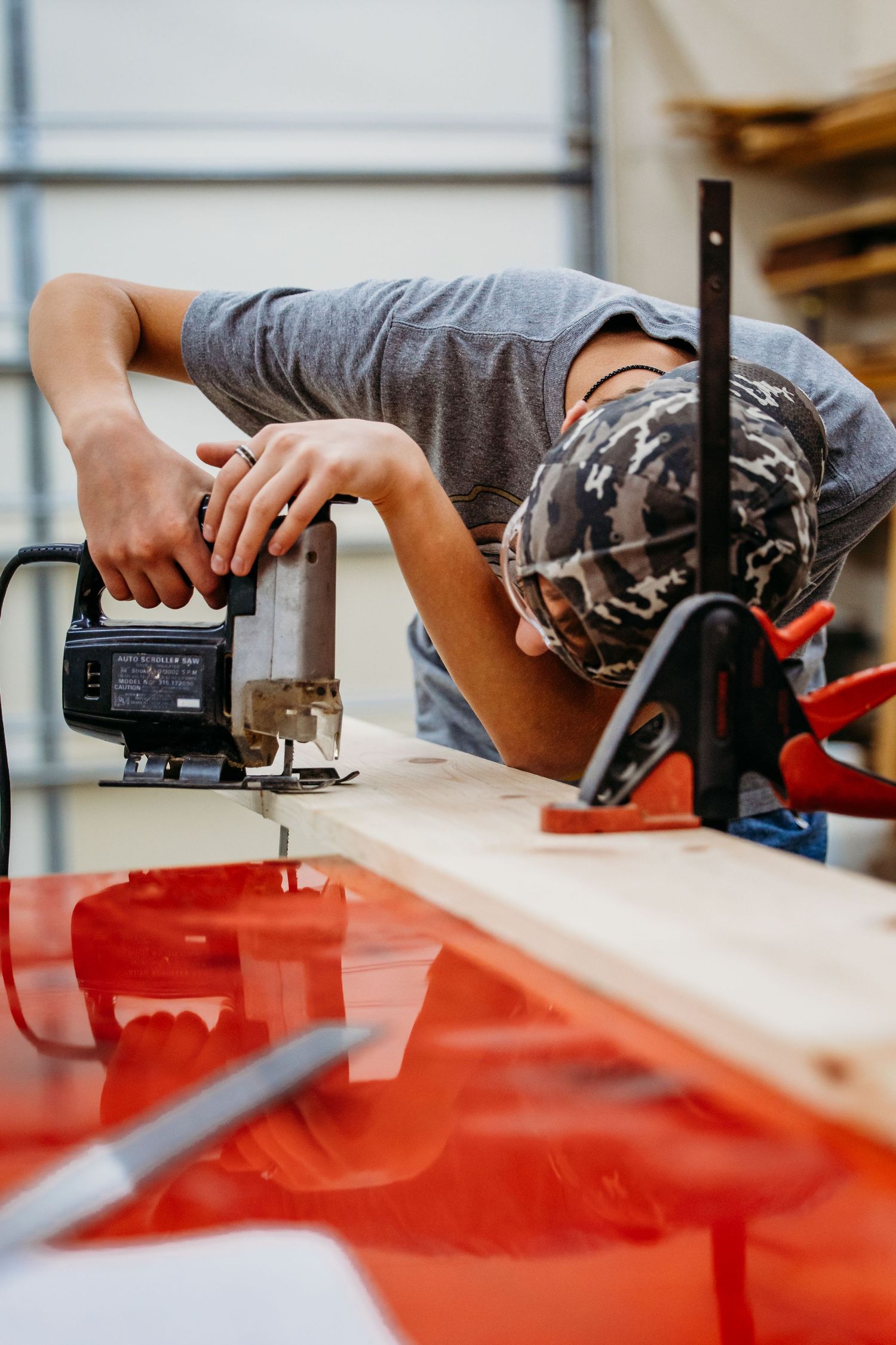Hands demonstrate how to use a power drill on a red workshop table surface from multiple angles.