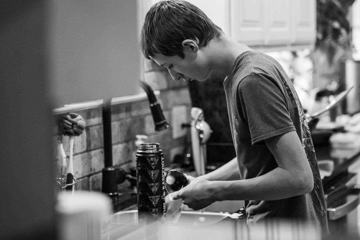 black and white images of a boy washing dishes