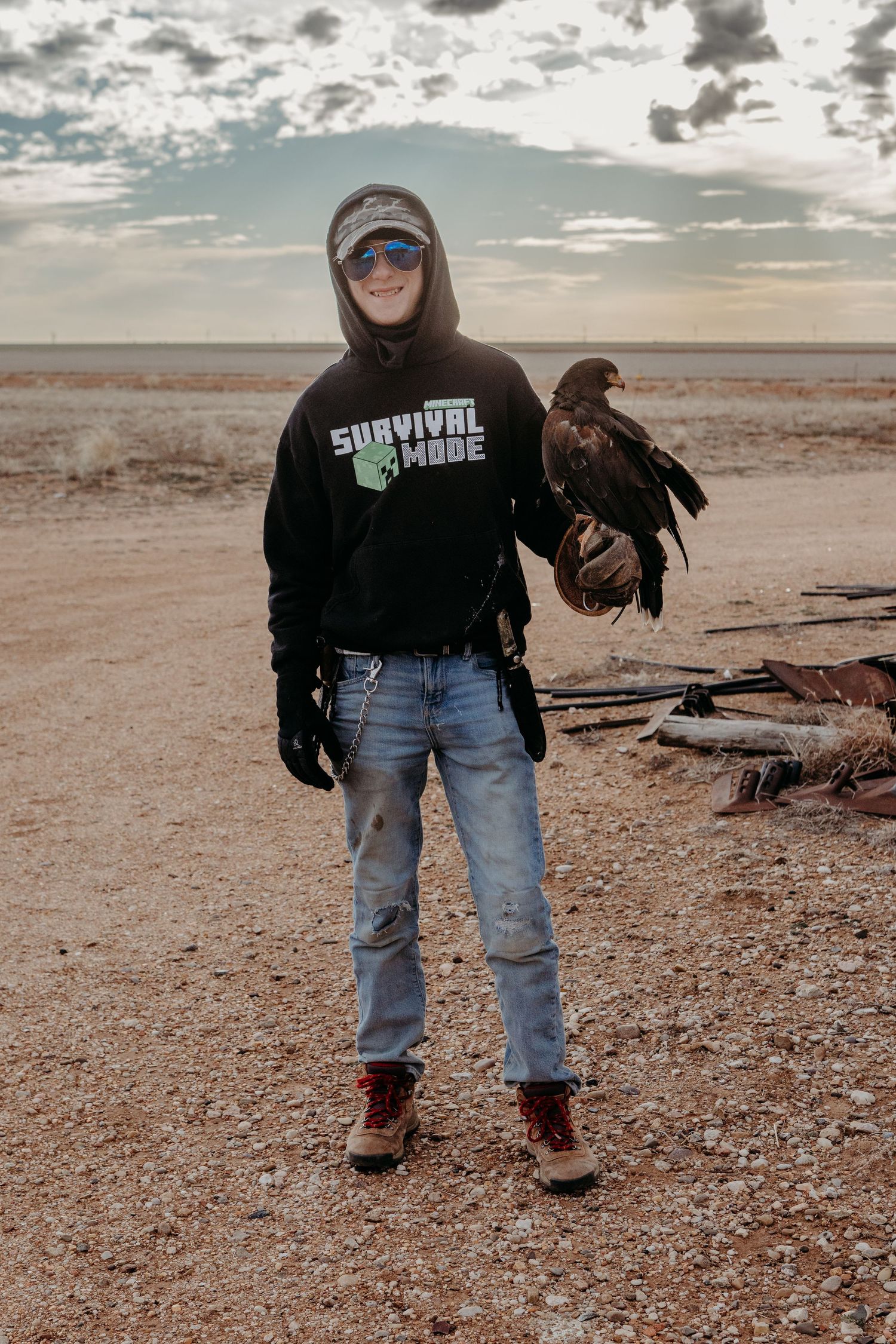 Three photos of a falconer in casual clothing handling a bird of prey on a desert terrain at sunset.