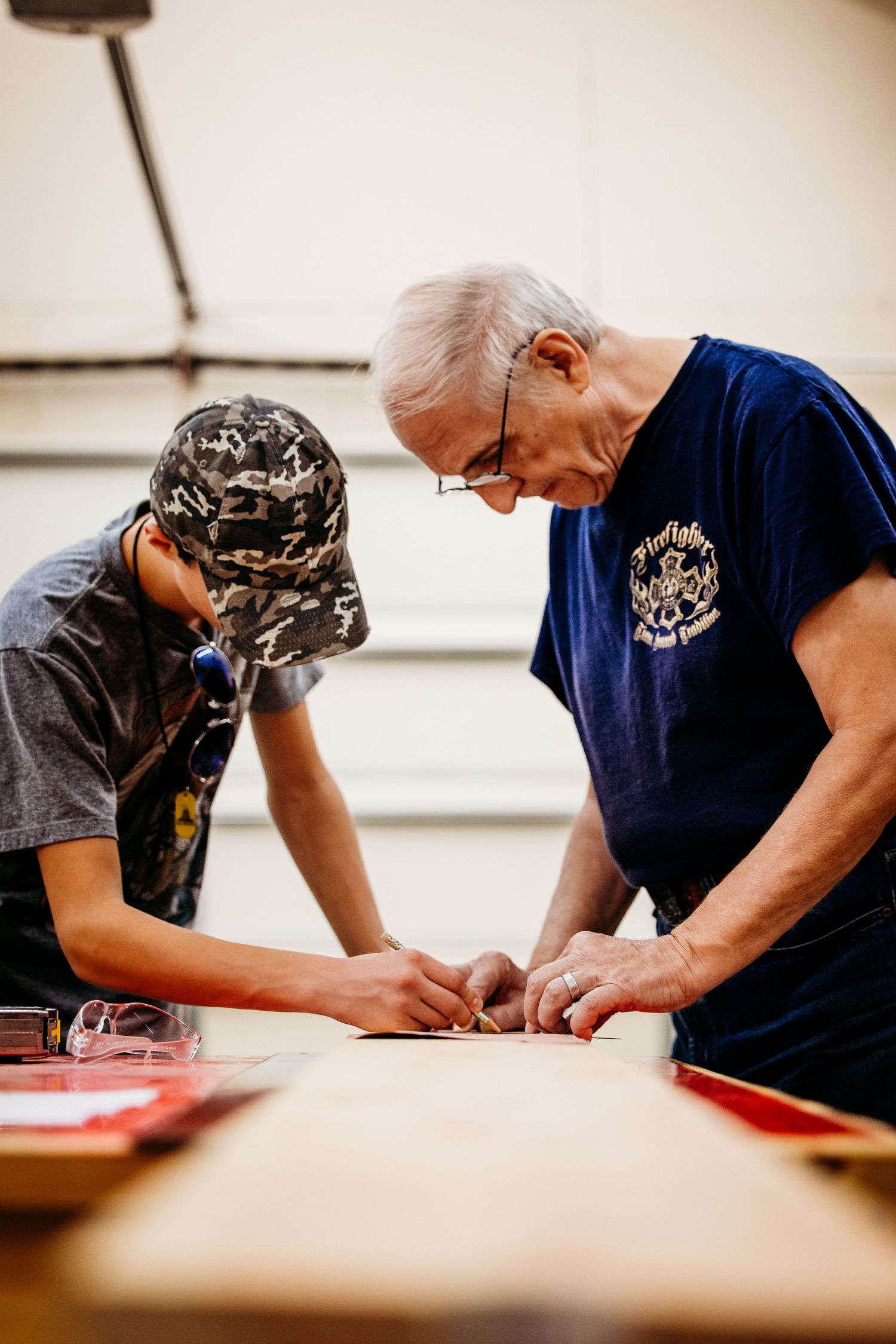 Two people working together at a table examining materials during a hands-on project or learning activity.