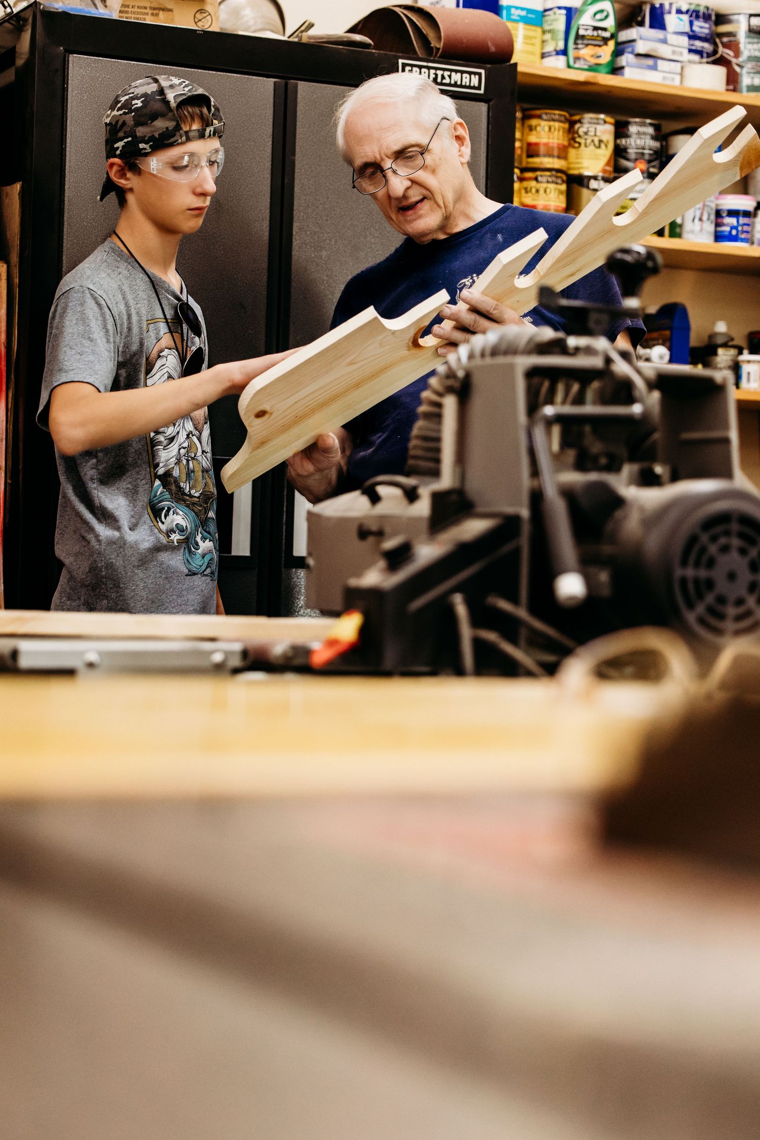 Student and teacher examine equipment in a woodworking laboratory while working on wooden construction projects.