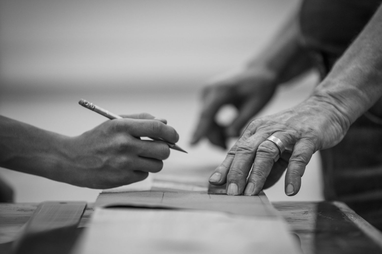 A series of black and white close-up shots showing hands marking measurements on wood