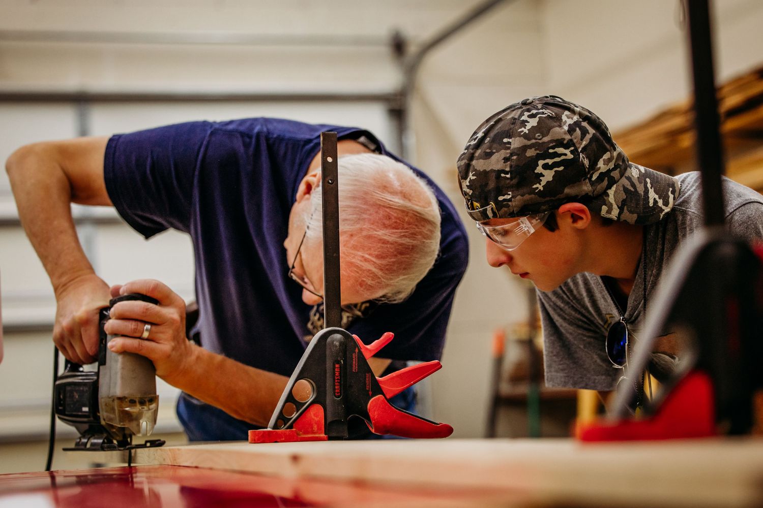 Grandfather teaching grandson how to use a saw captured by Amanda Corlew Photography