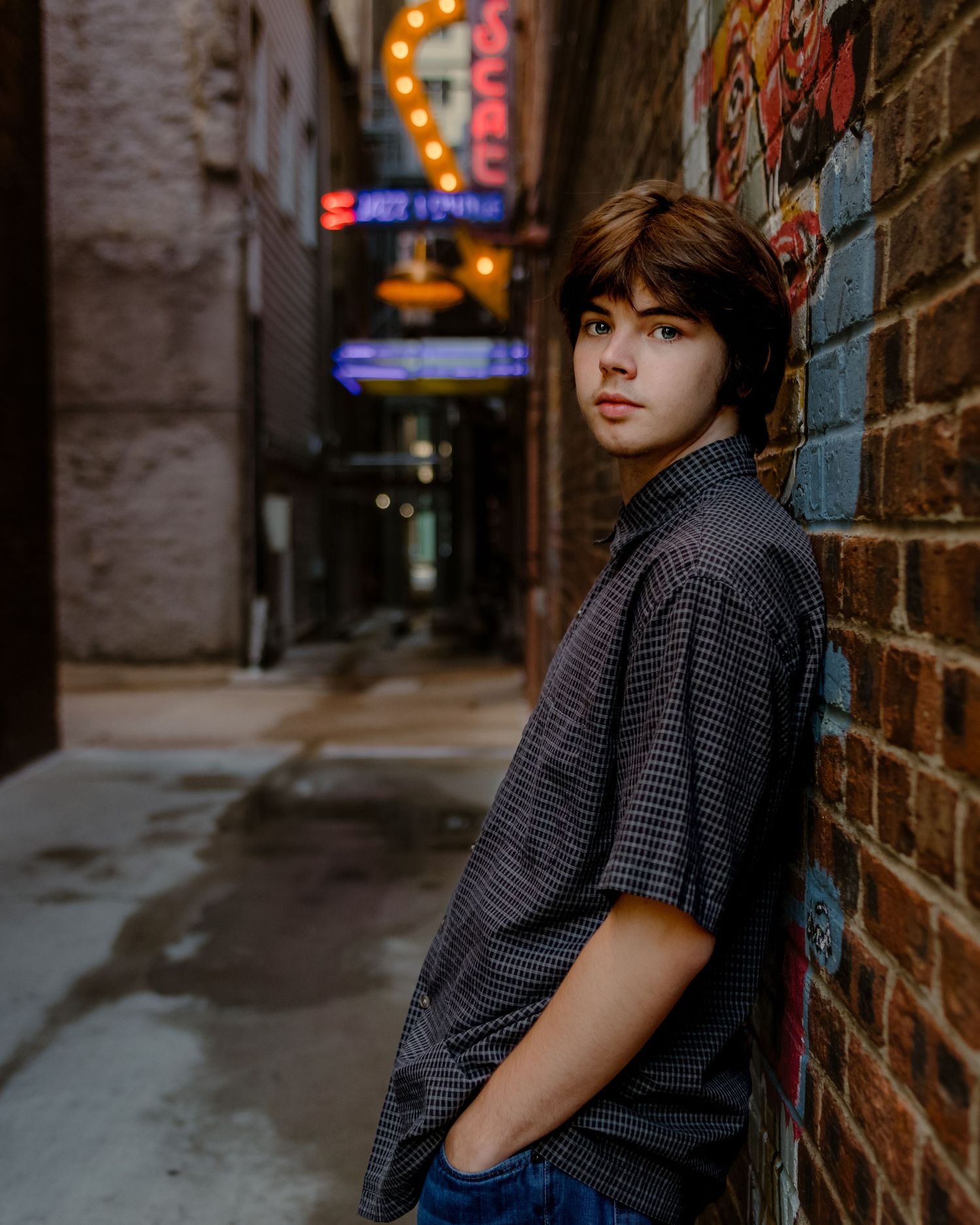 boy leaning against brick wall at Senior Portrait session in Scat Jazz Lounge Alley