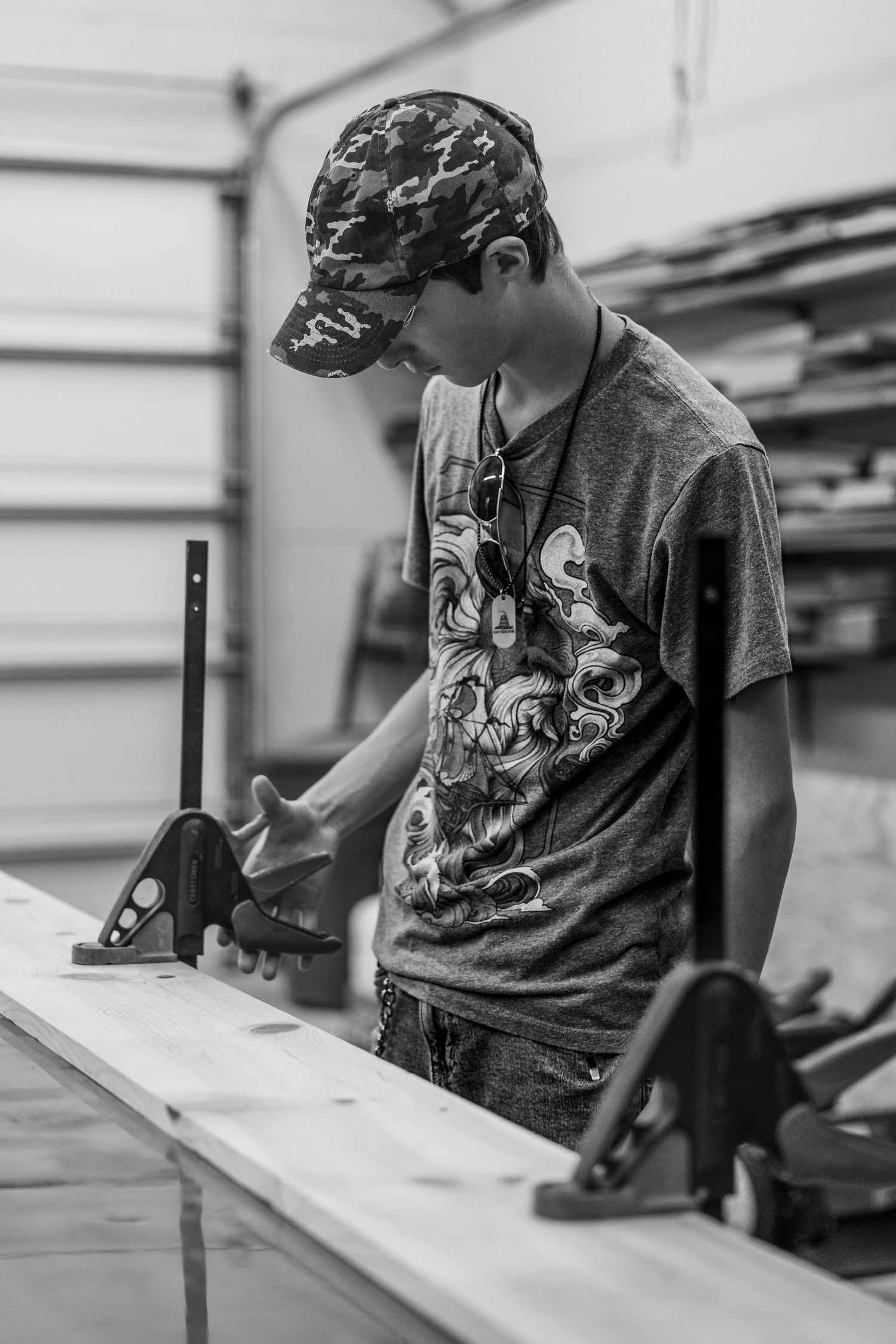 Student uses a ruler and pencil to make precise measurements on a piece of work at a drafting table in black and white.