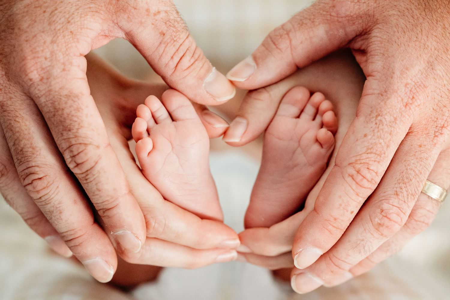 Close-up of parents hands holding their newborn baby's feet at their in-home newborn session in Watauga, TX