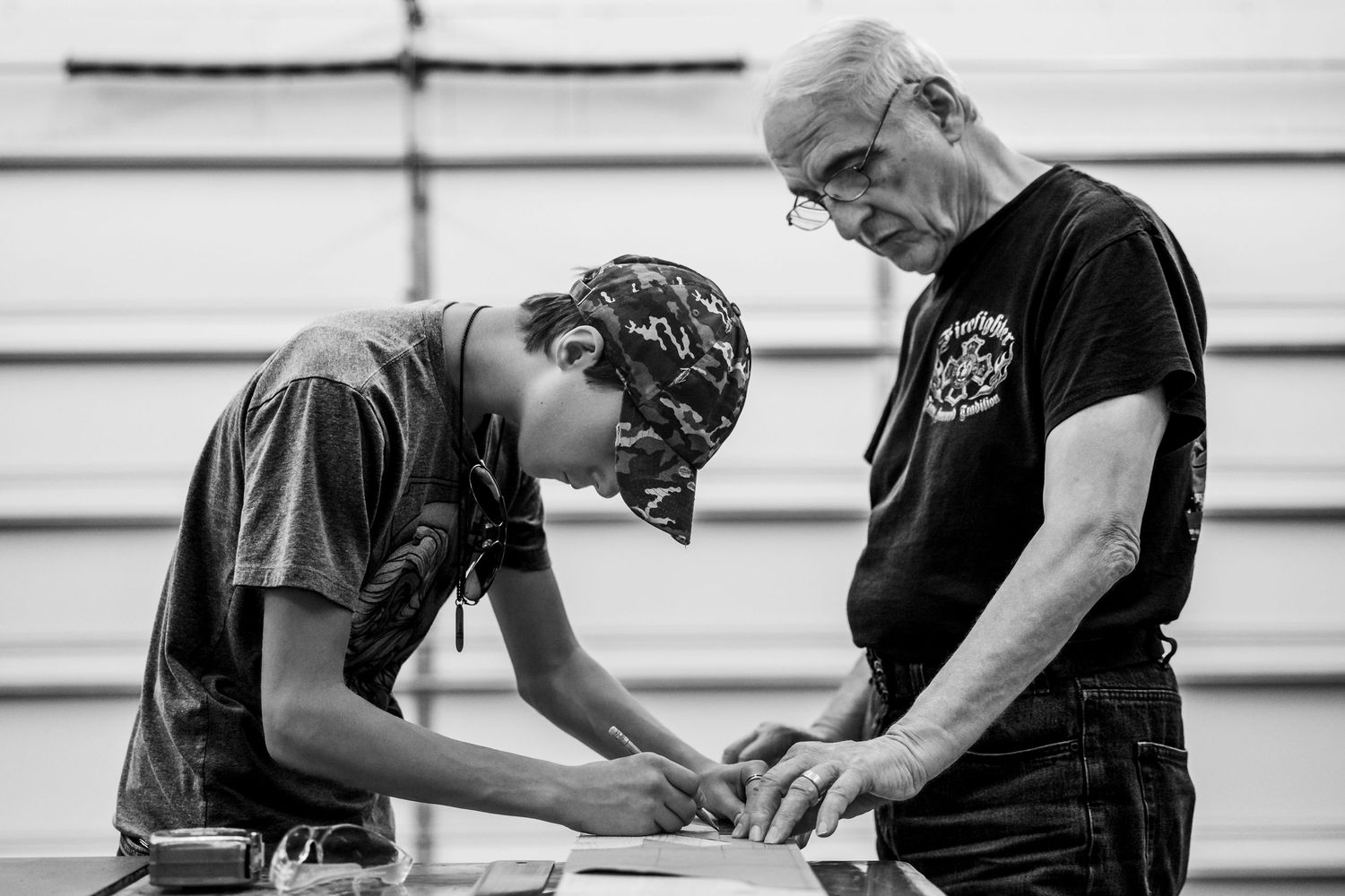 Two people marking measurements on wood for a craft project