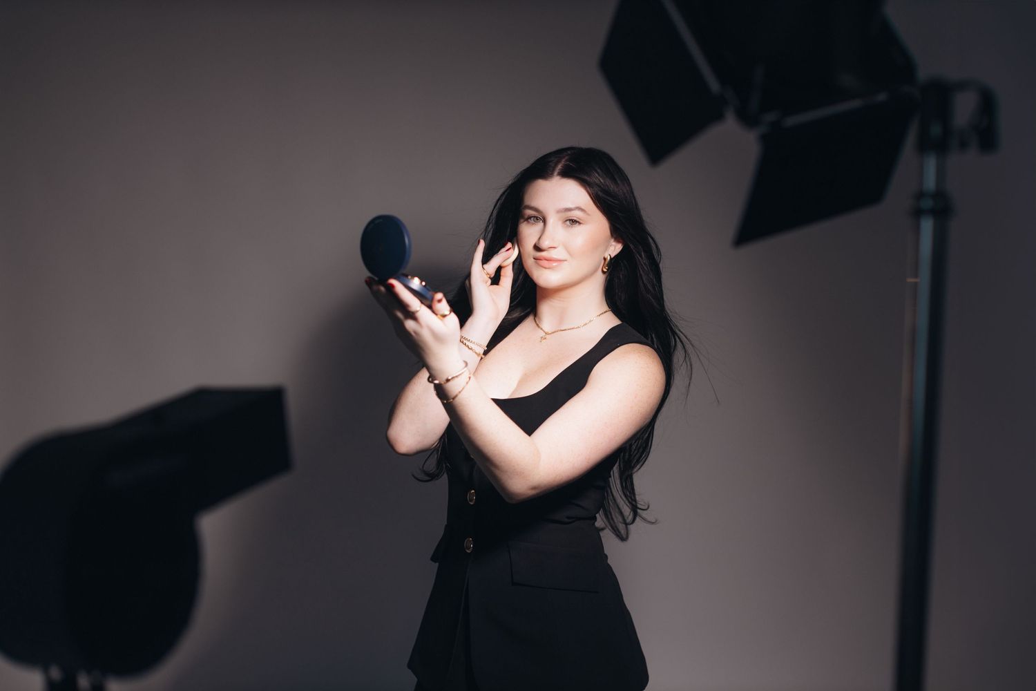 Professional photography studio setup with lighting equipment and model in black dress.