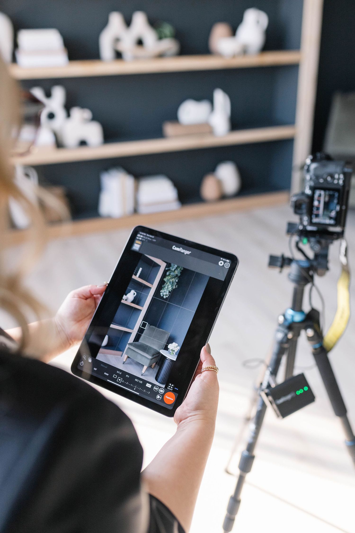 Overhead view of an interiors photographer reviewing composition on an iPad, ensuring every detail is captured with prec
