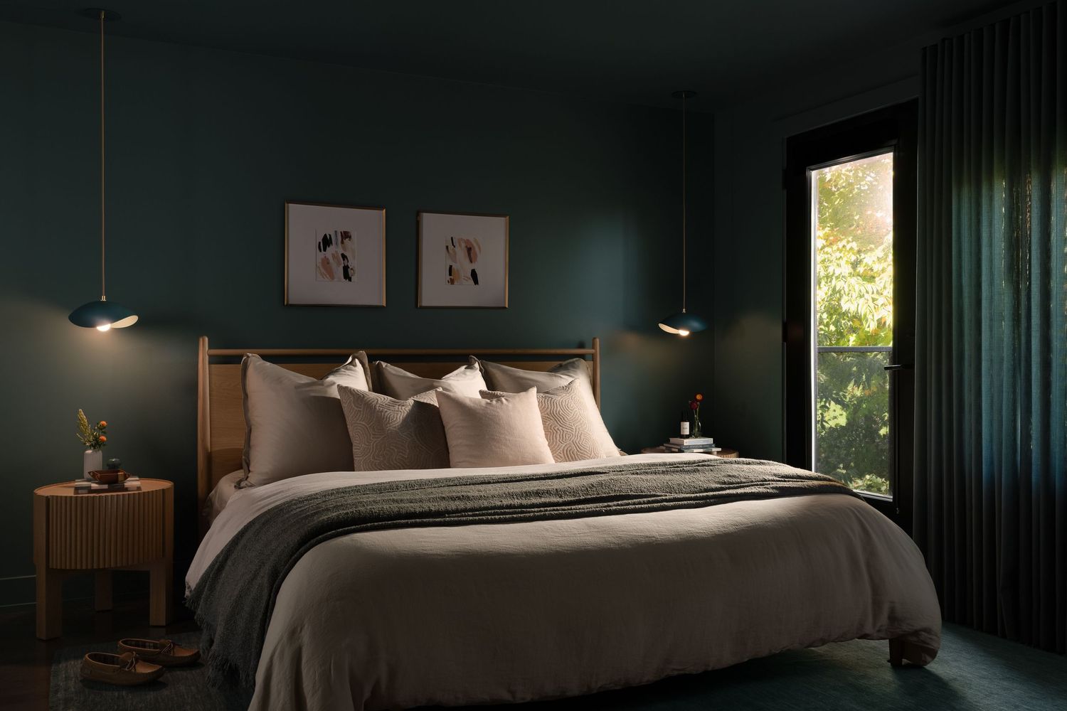 A modern moody bedroom with dark teal walls, plush bedding, and large windows overlooking a scenic view in Ottawa