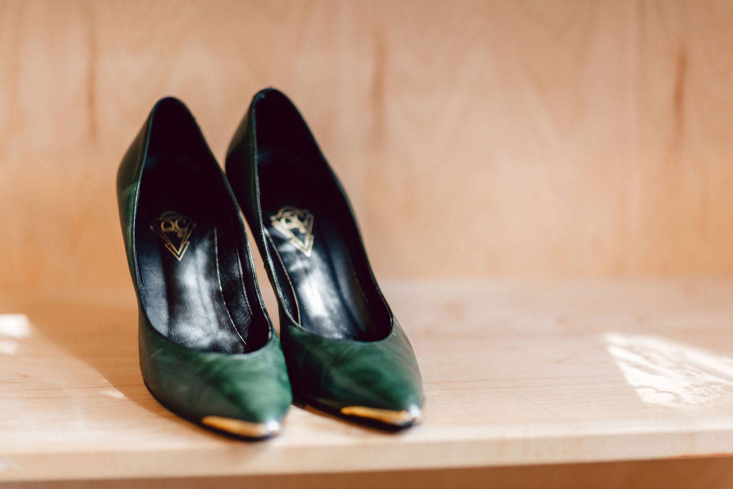 A pair of gold-toed green vintage heels on a shelf in the sunlight from a New England elopement.