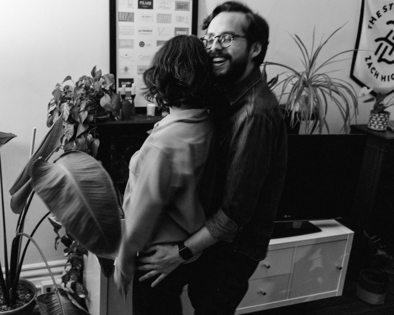 A black and white photo of a couple in their New England apartment dancing and smiling together.