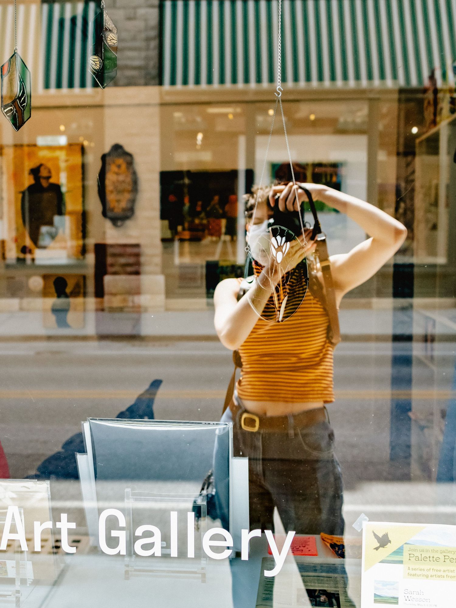 Ro Tatchi wears an N-95 mask and a yellow and maroon striped shirt while photographing the outside of a Vermont art studio.