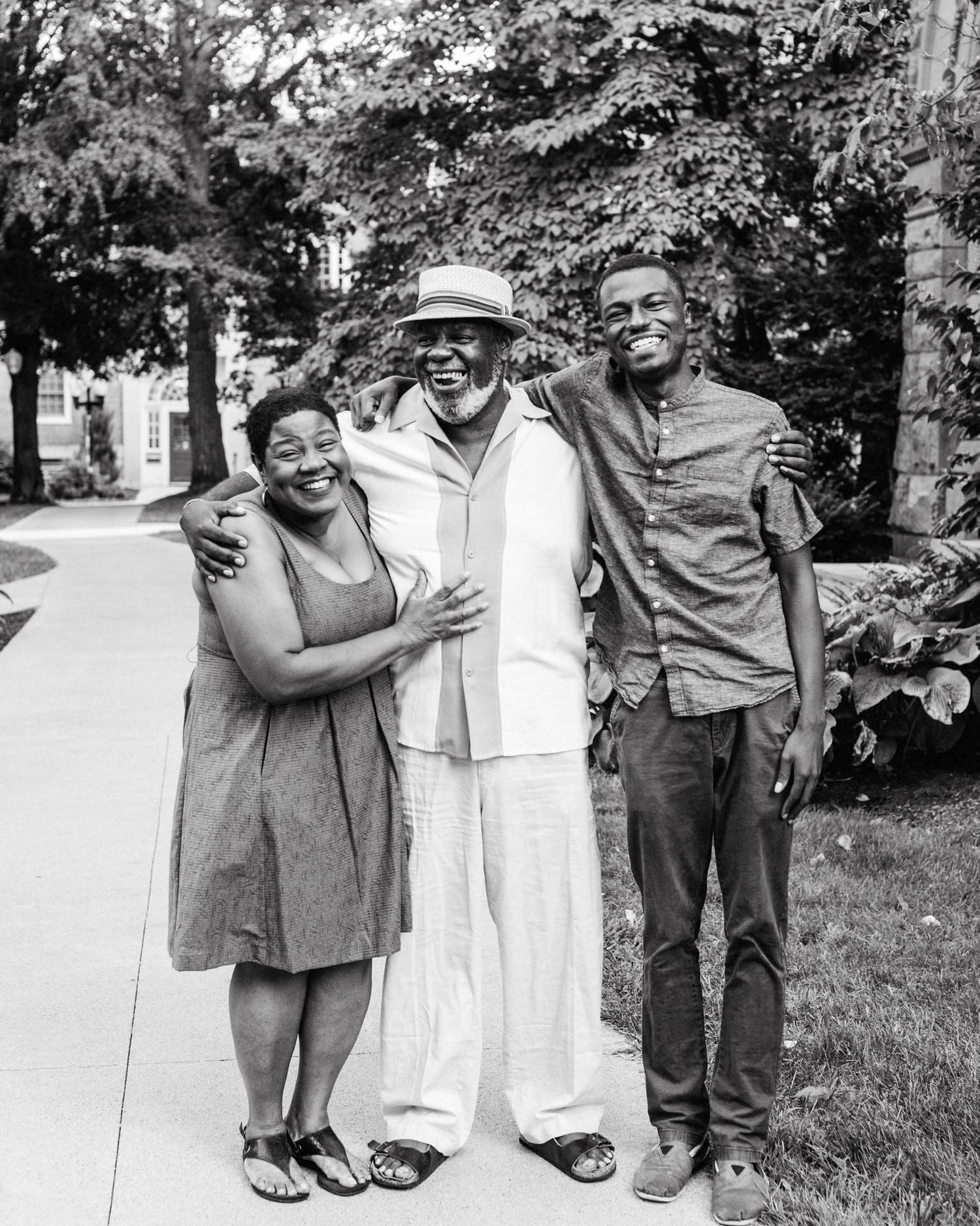 Black and white photo of a Black family hugging on a sidewalk in Troy, NY