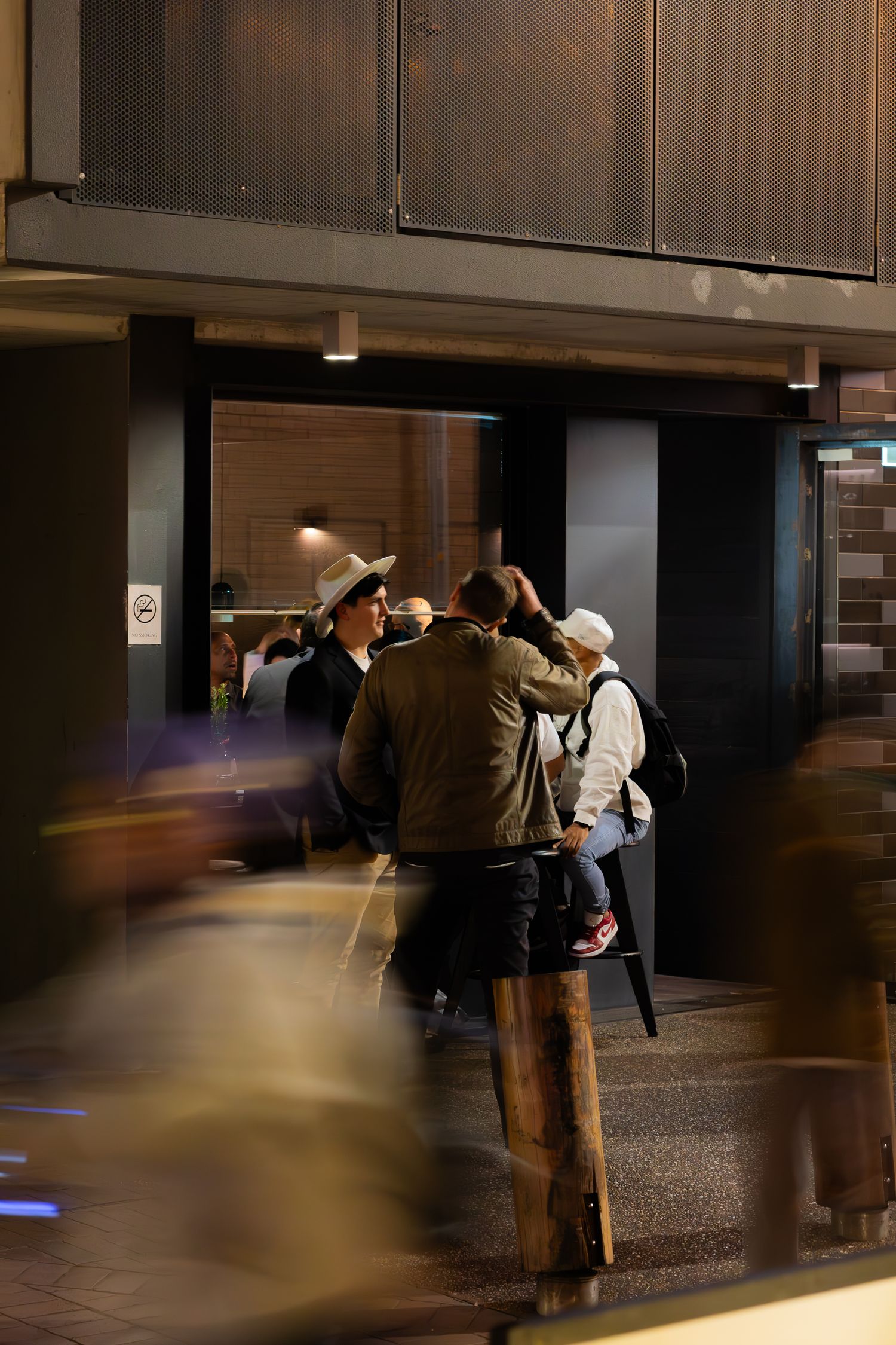 Dimly lit bar entrance with people gathering in casual attire.
