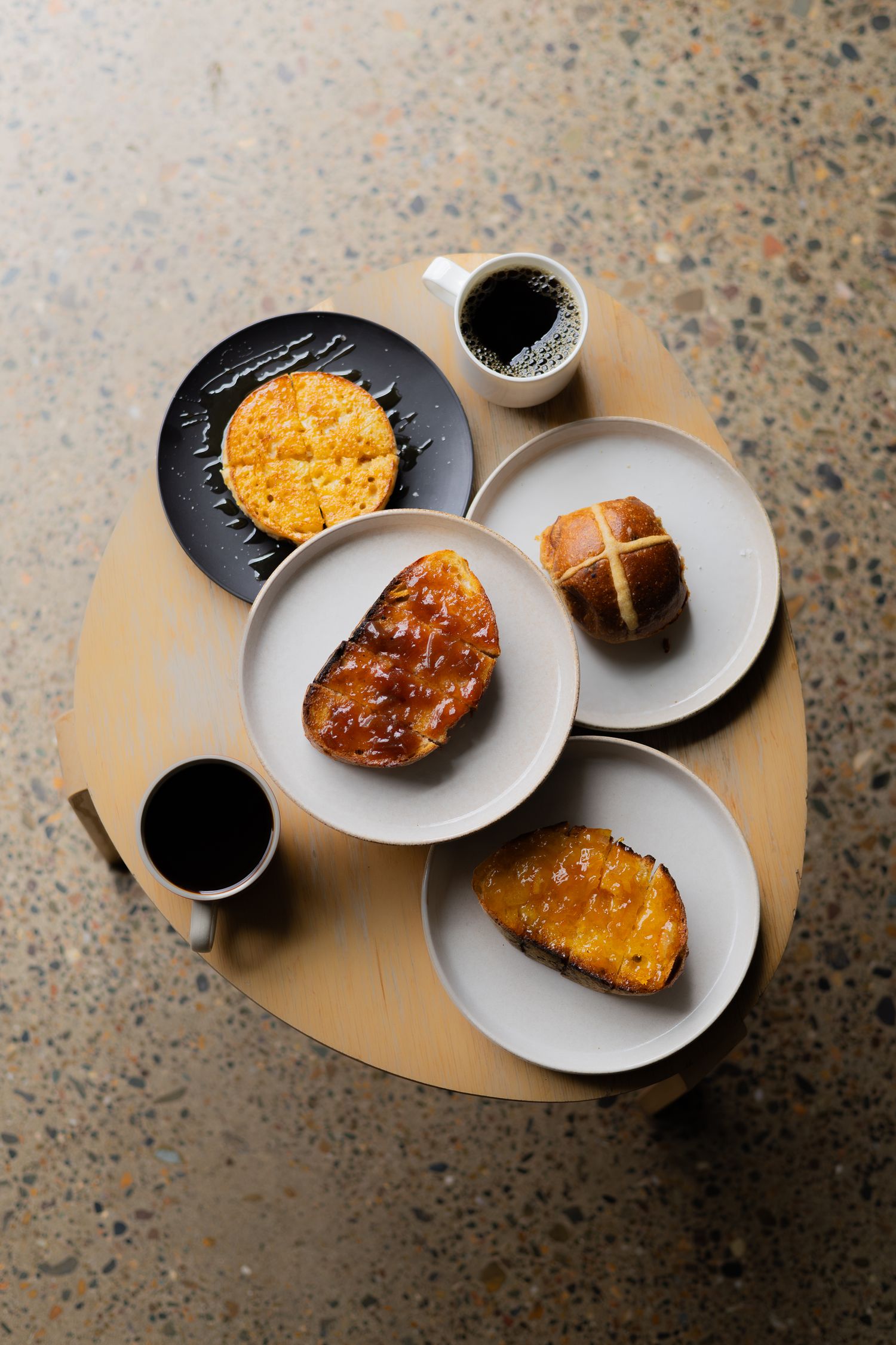 Top view of breakfast setup with various pastries and coffee on beige round table.