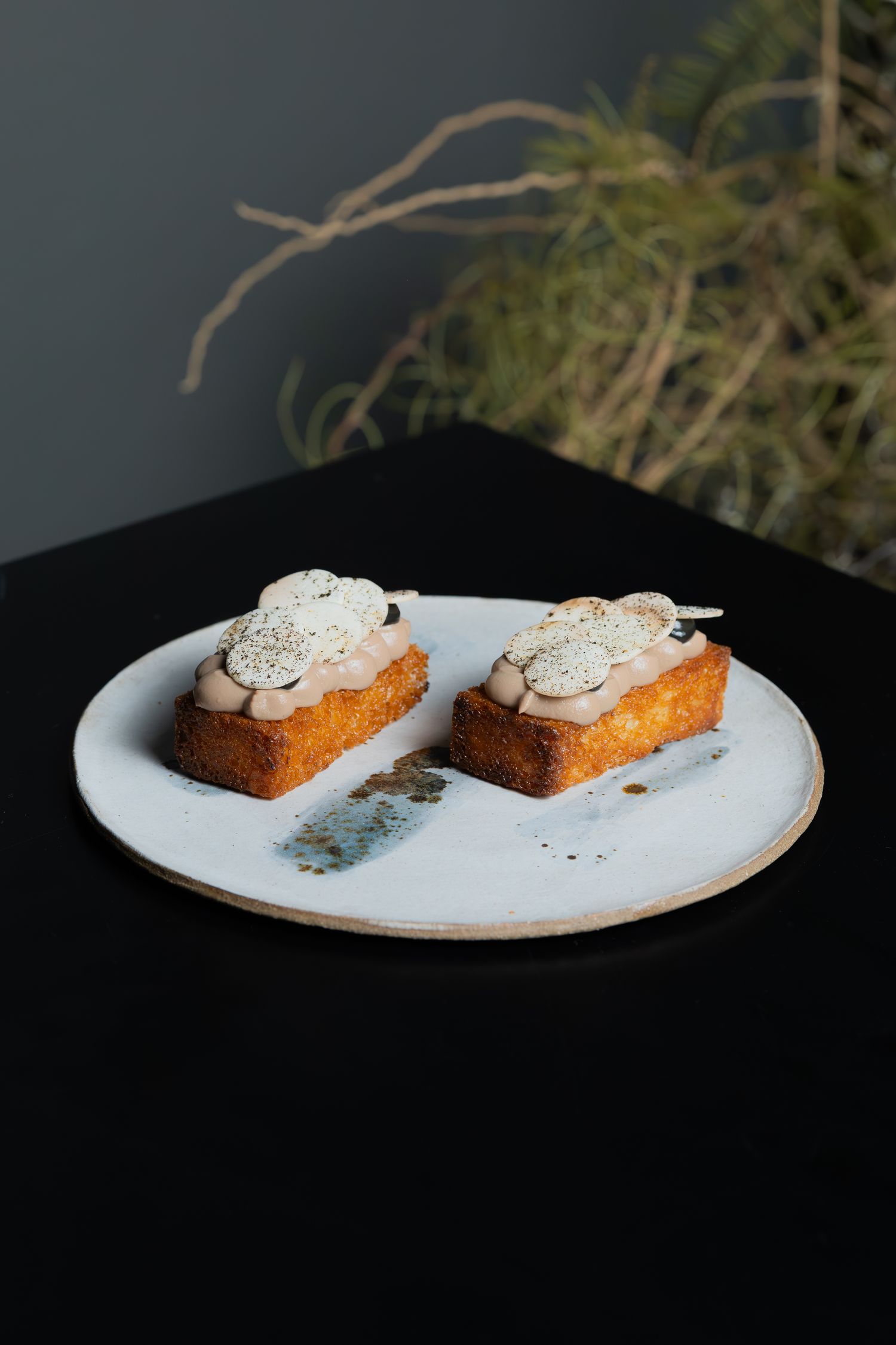 Two elegant dessert slices topped with whipped cream and macarons on a white plate.