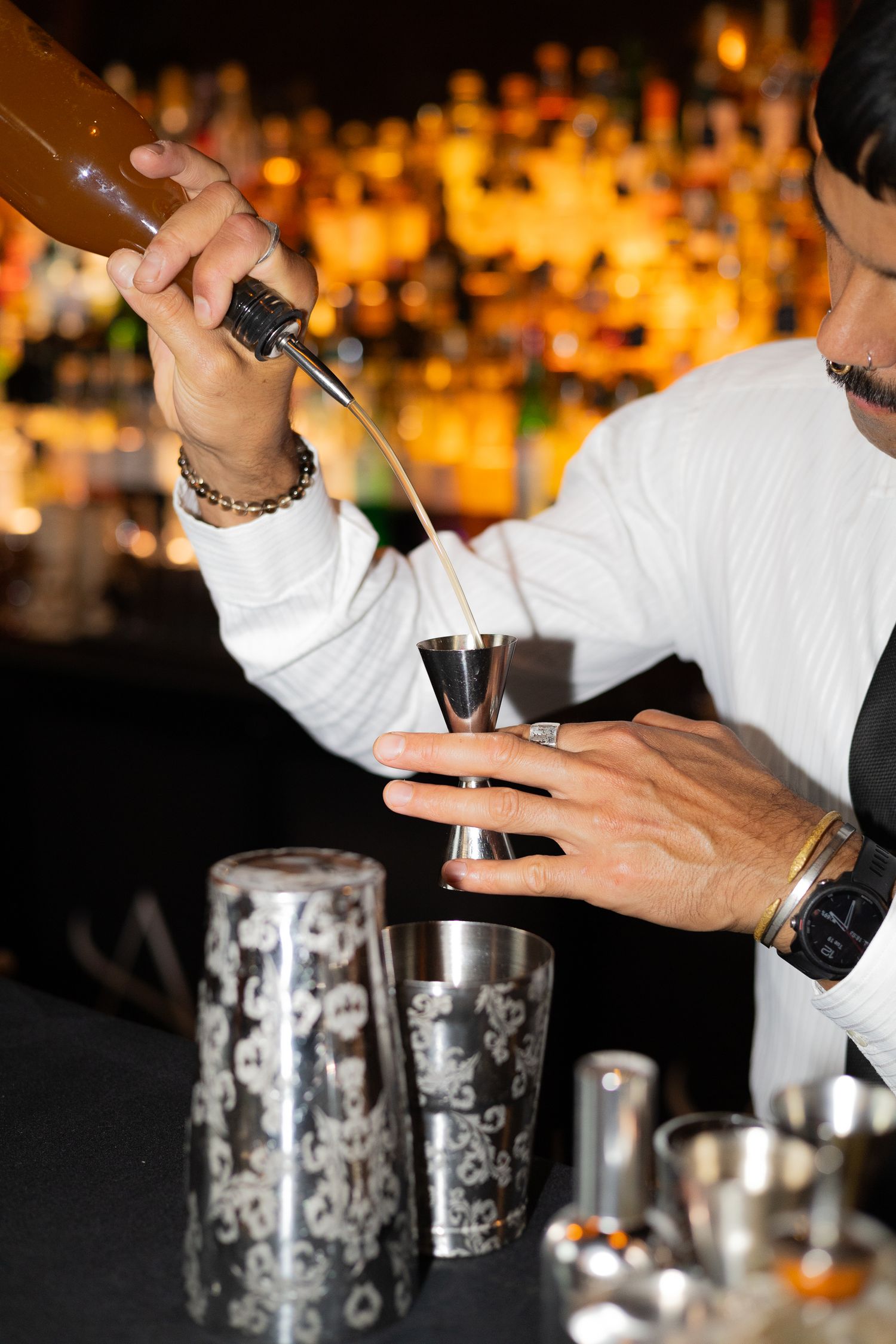 Bartender pouring a cocktail with precise technique using professional bar tools.