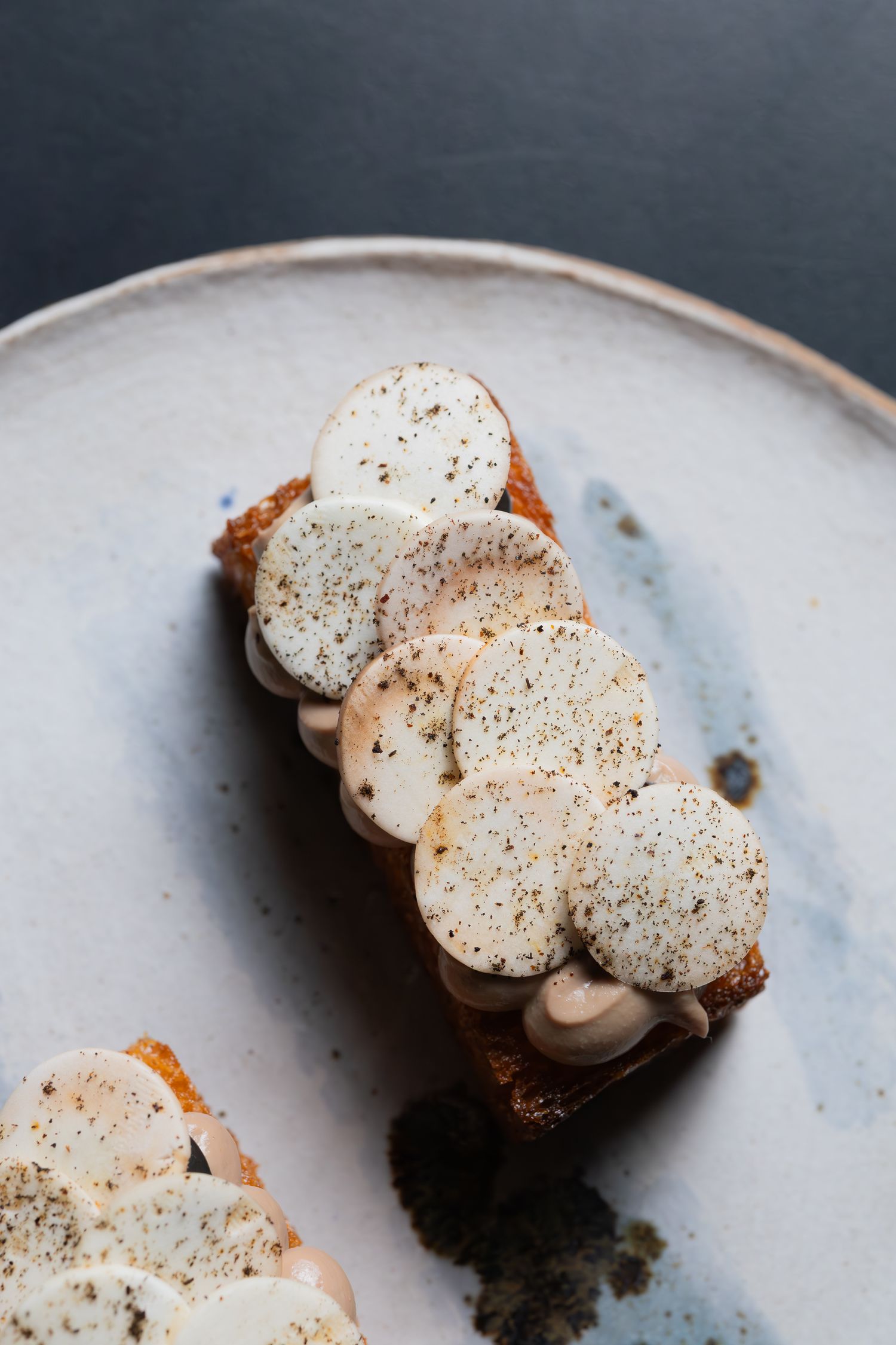 Artisanal dessert topped with speckled cream dollops on a rustic ceramic plate.