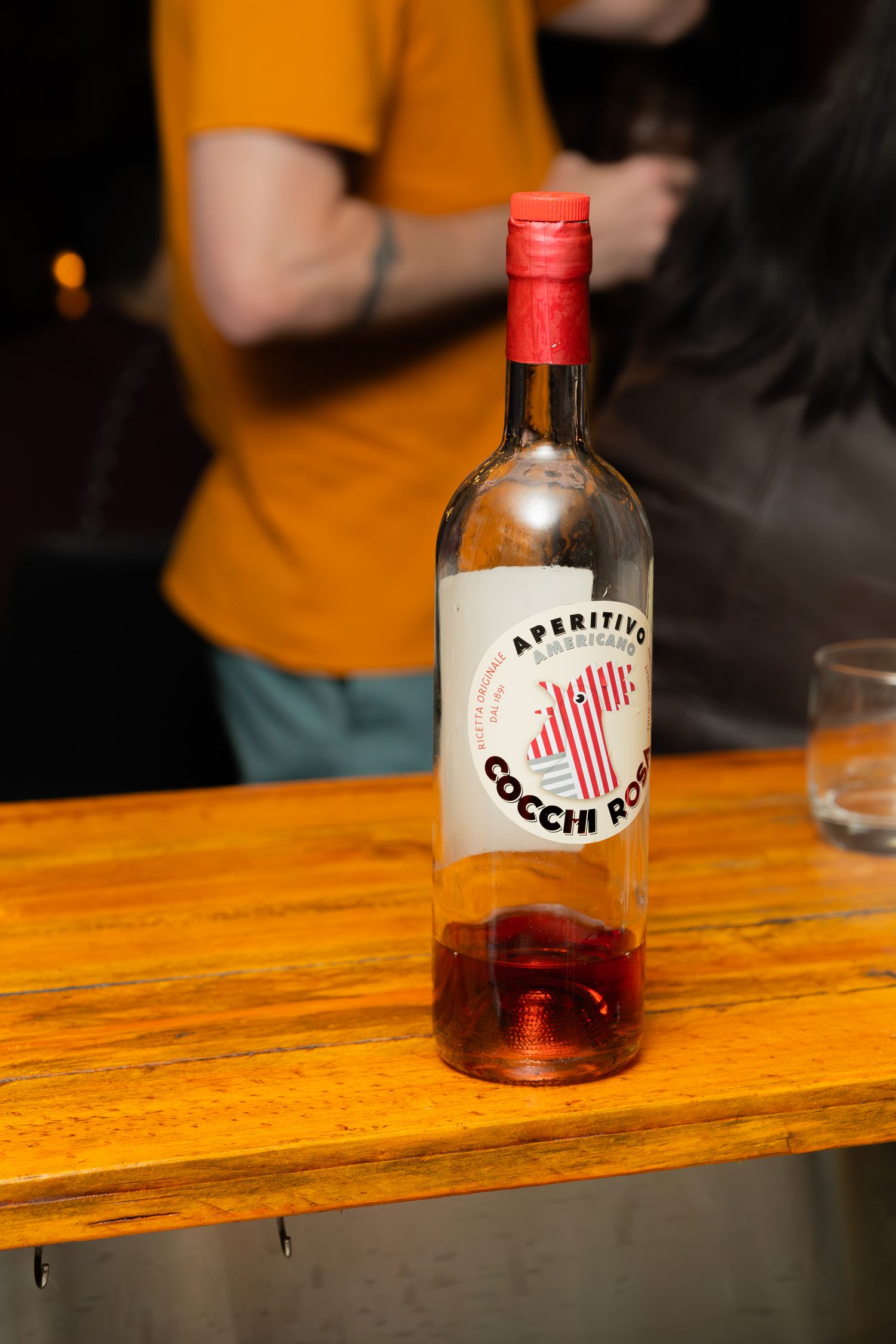 Bottle of Cocchi aperitif wine displayed on wooden bar surface.