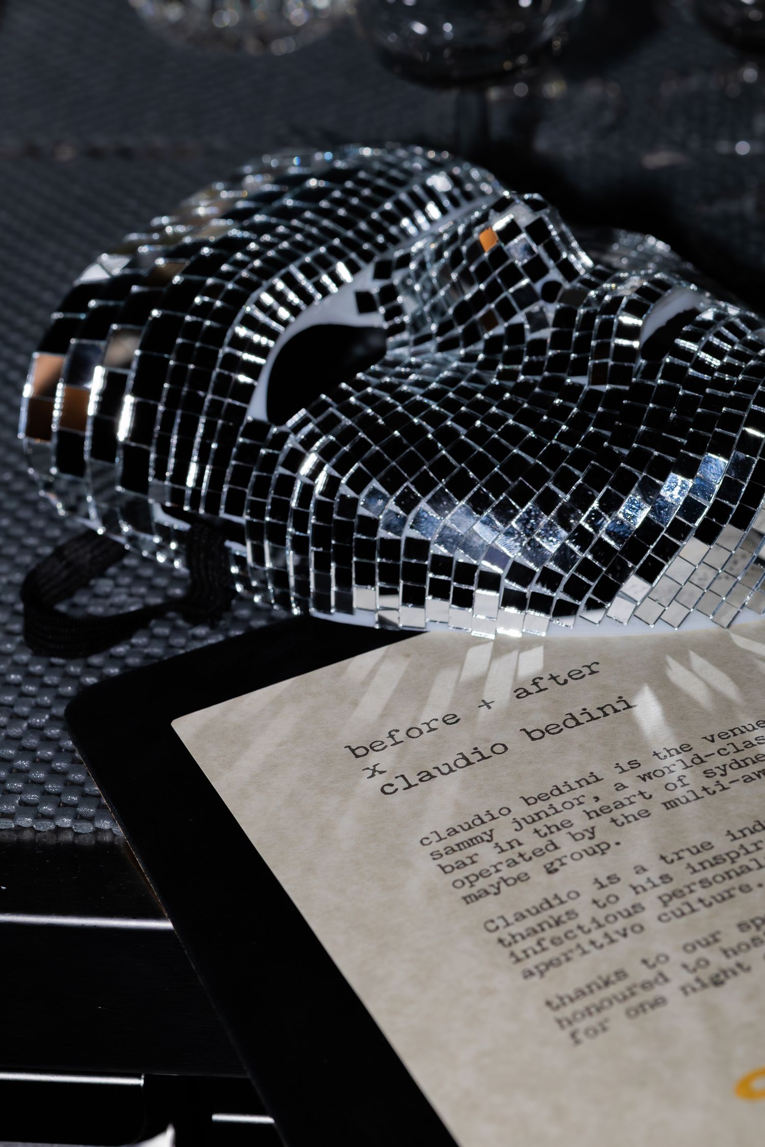 A disco ball style mosaic object next to a menu on a dark table.