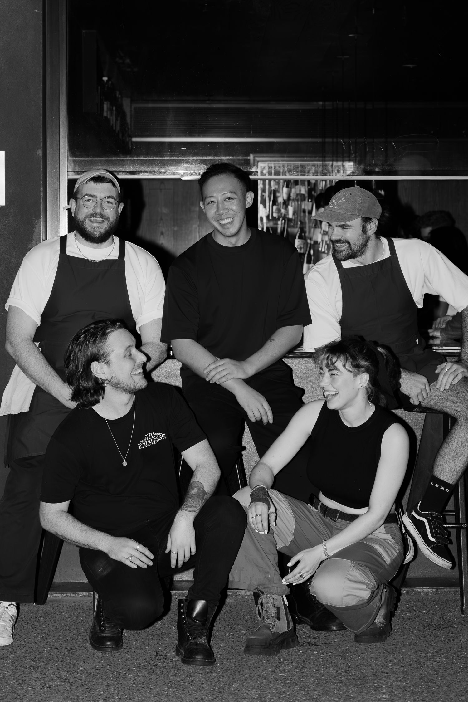 Group of bar staff posing together in black and white photo.