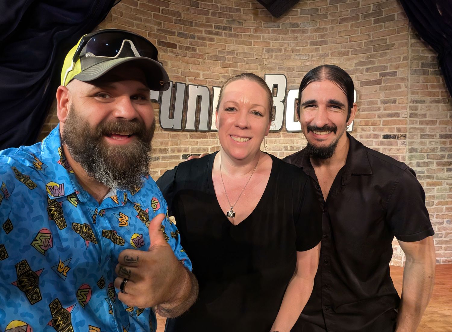 Graeson Mcgaha comedian. Three smiling people pose together at Funny Bone comedy club, man in blue floral shirt giving thumbs up.