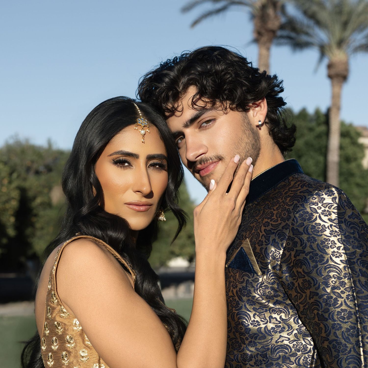 Close-up of a couple in Indian festive attire sharing an intimate moment near palm trees.