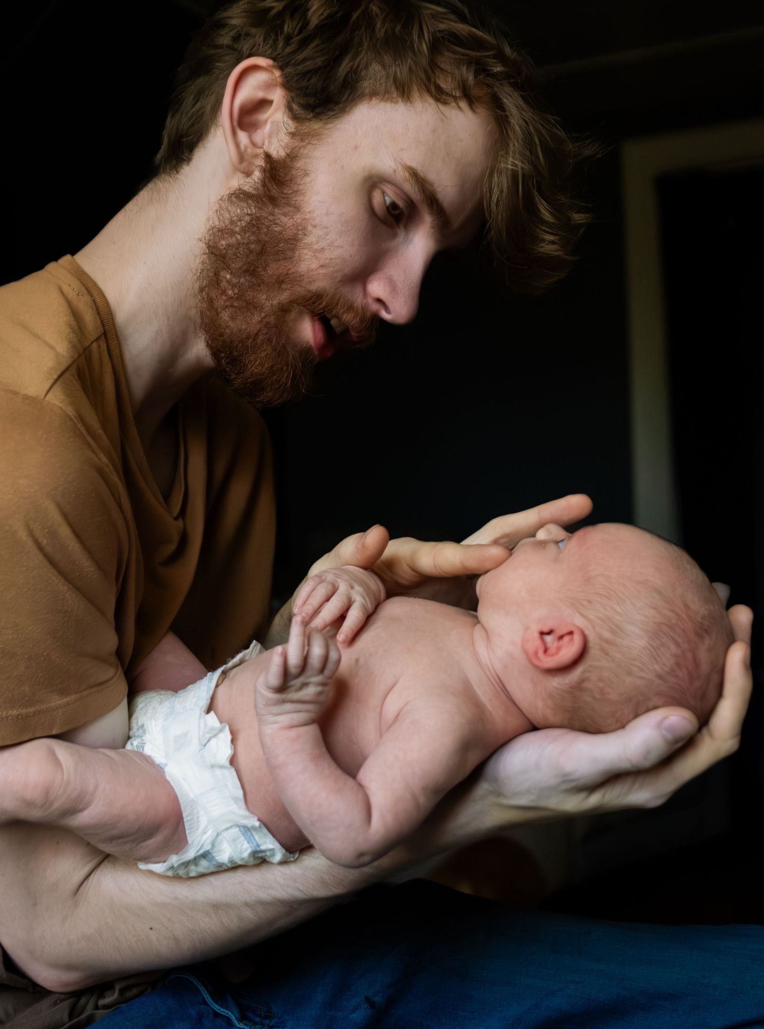 Father holding his baby wearing a diaper during a postpartum lifestyle photography session in Elmira, NY