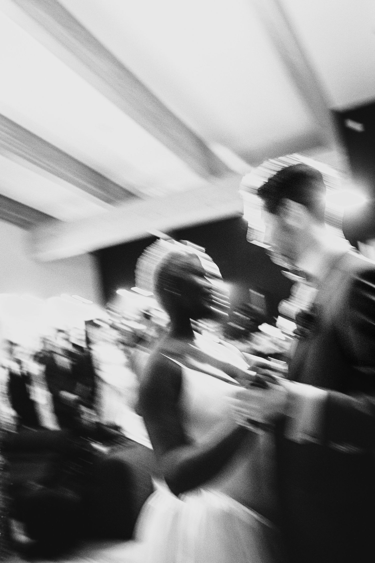 Motion blur black and white photo of wedding couple dancing at their indoor reception celebration.