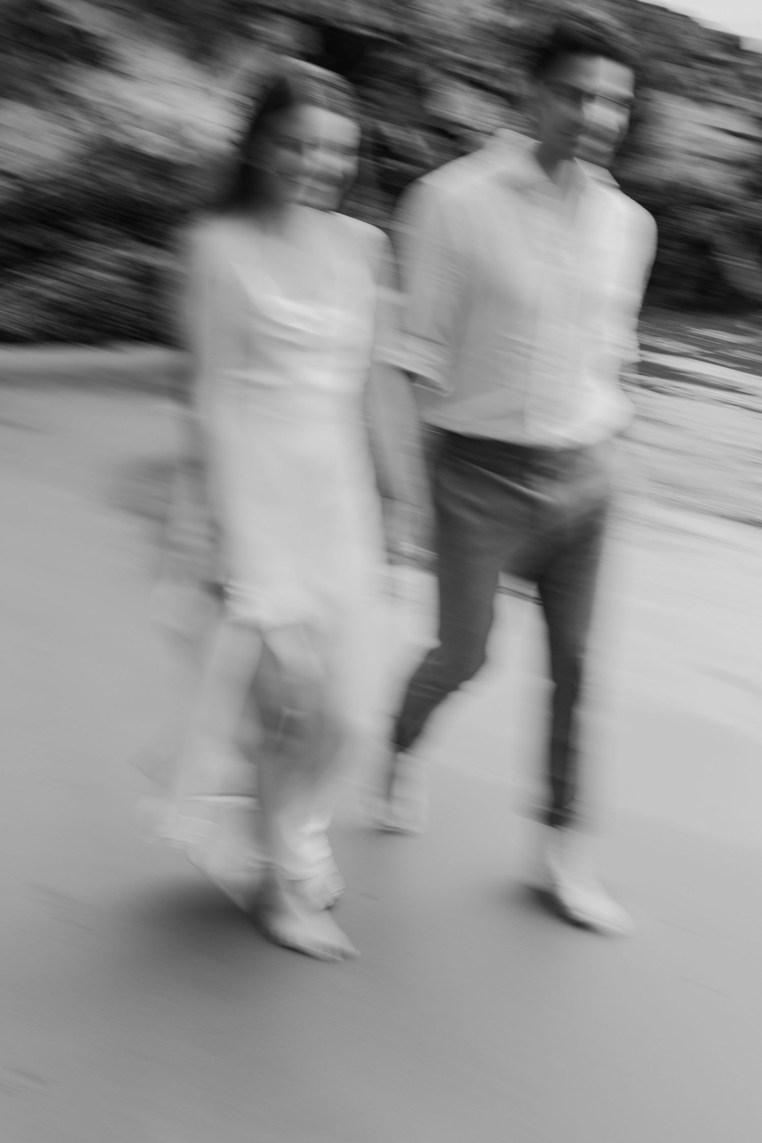 Black and white motion blur photo of a couple walking together, creating an artistic dreamy effect.